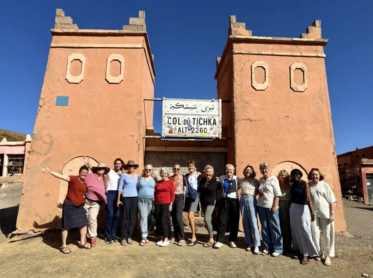 Group of people standing in front of the old gates of the Tizi Tnifert pass near Tighza, Morocco, during the day with clear skies.