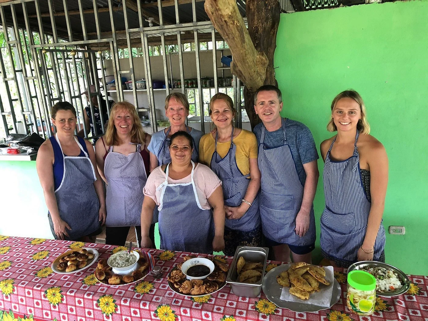 Group of women sitting on a boat with hills in the background, some wearing life jackets, sunglasses, and hats, on a sunny day.