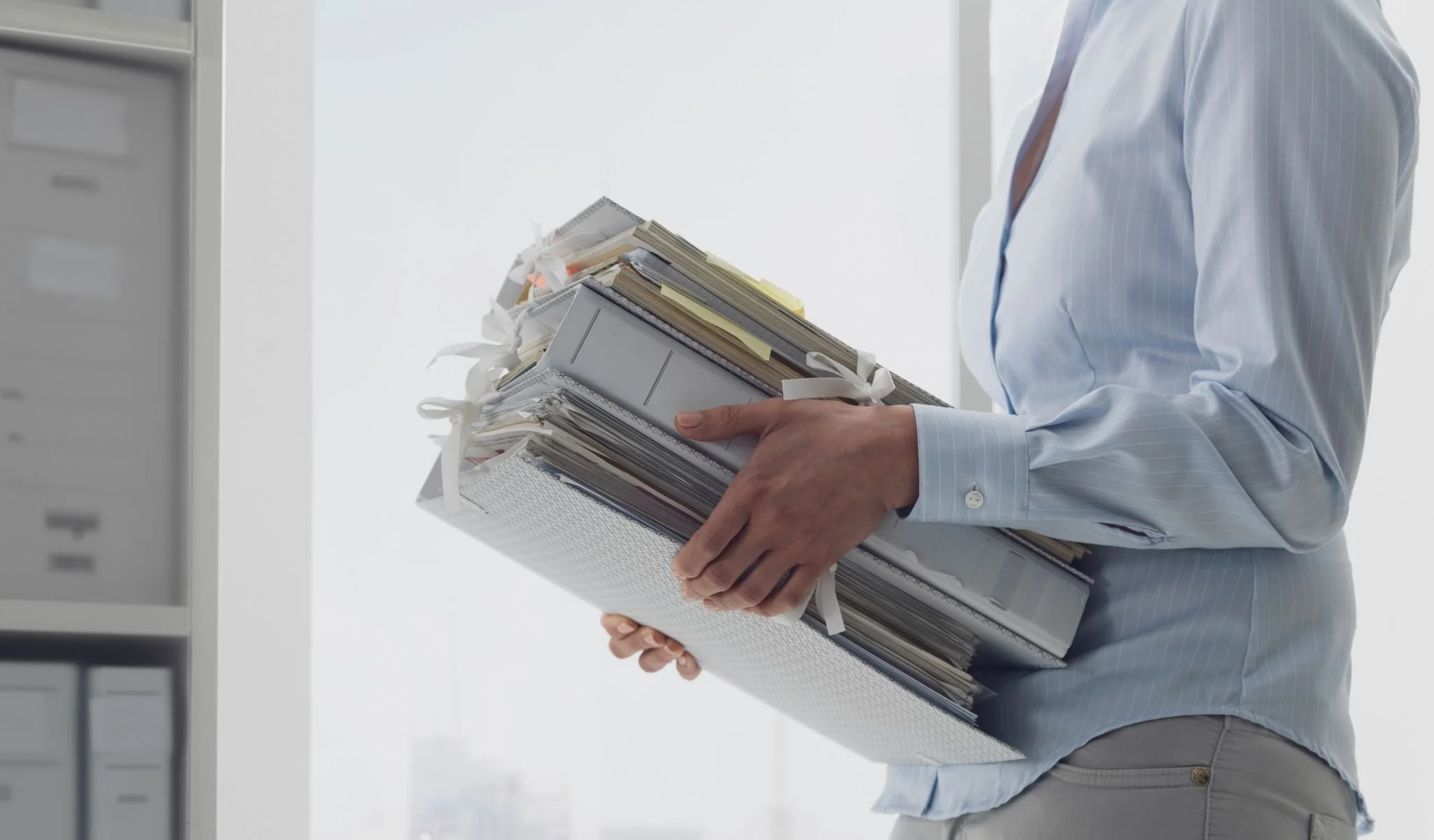 Executive carrying multiple folders representing workload strain and hiring capacity challenges