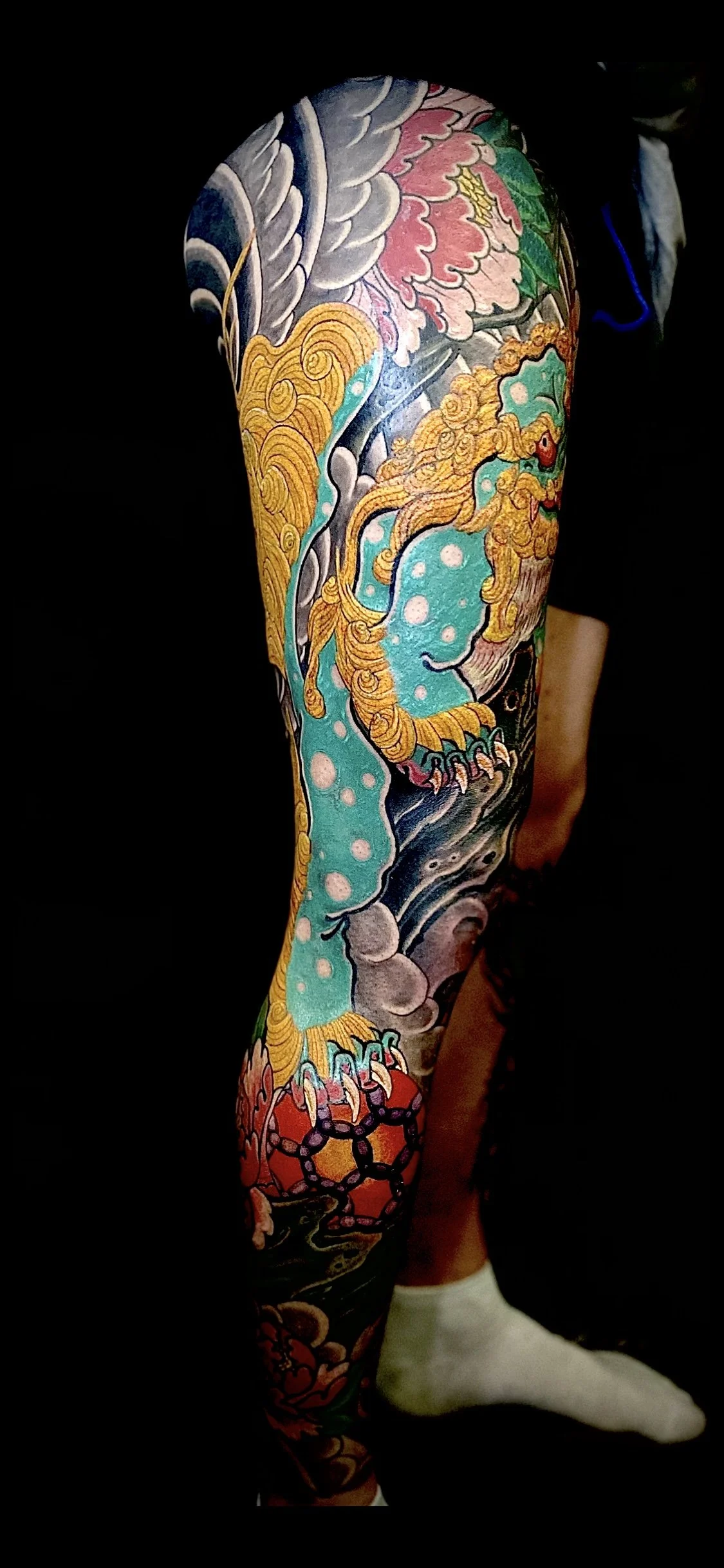 Colorful tattoo sleeve featuring a tiger, lotus flowers, and traditional Japanese-style waves and clouds.