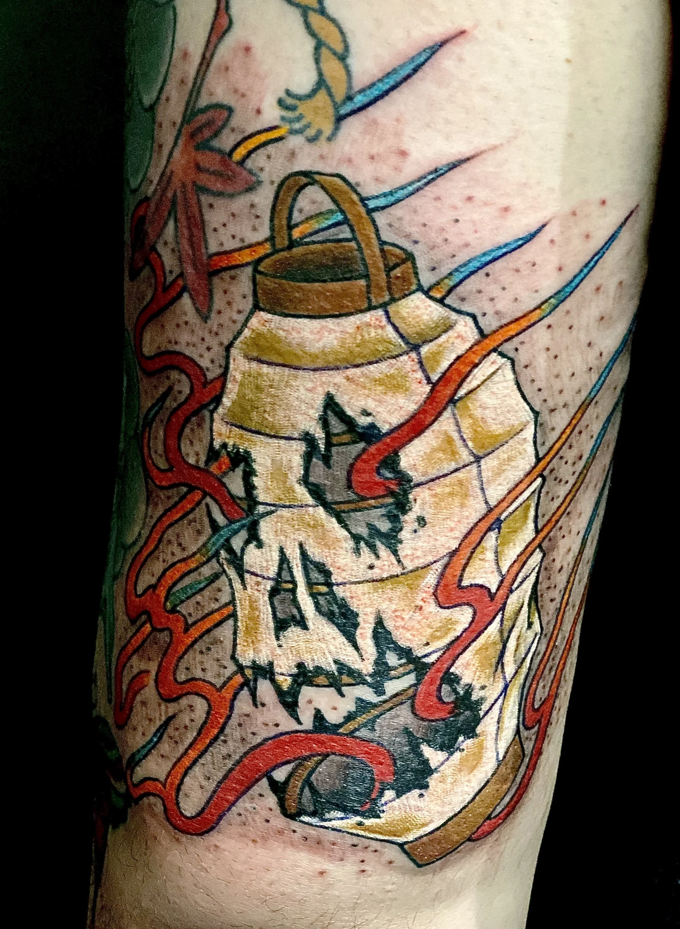 Colorful tattoo of a shattered beer can with exposed tab, surrounded by red, yellow, and blue lines, on a person's upper arm.