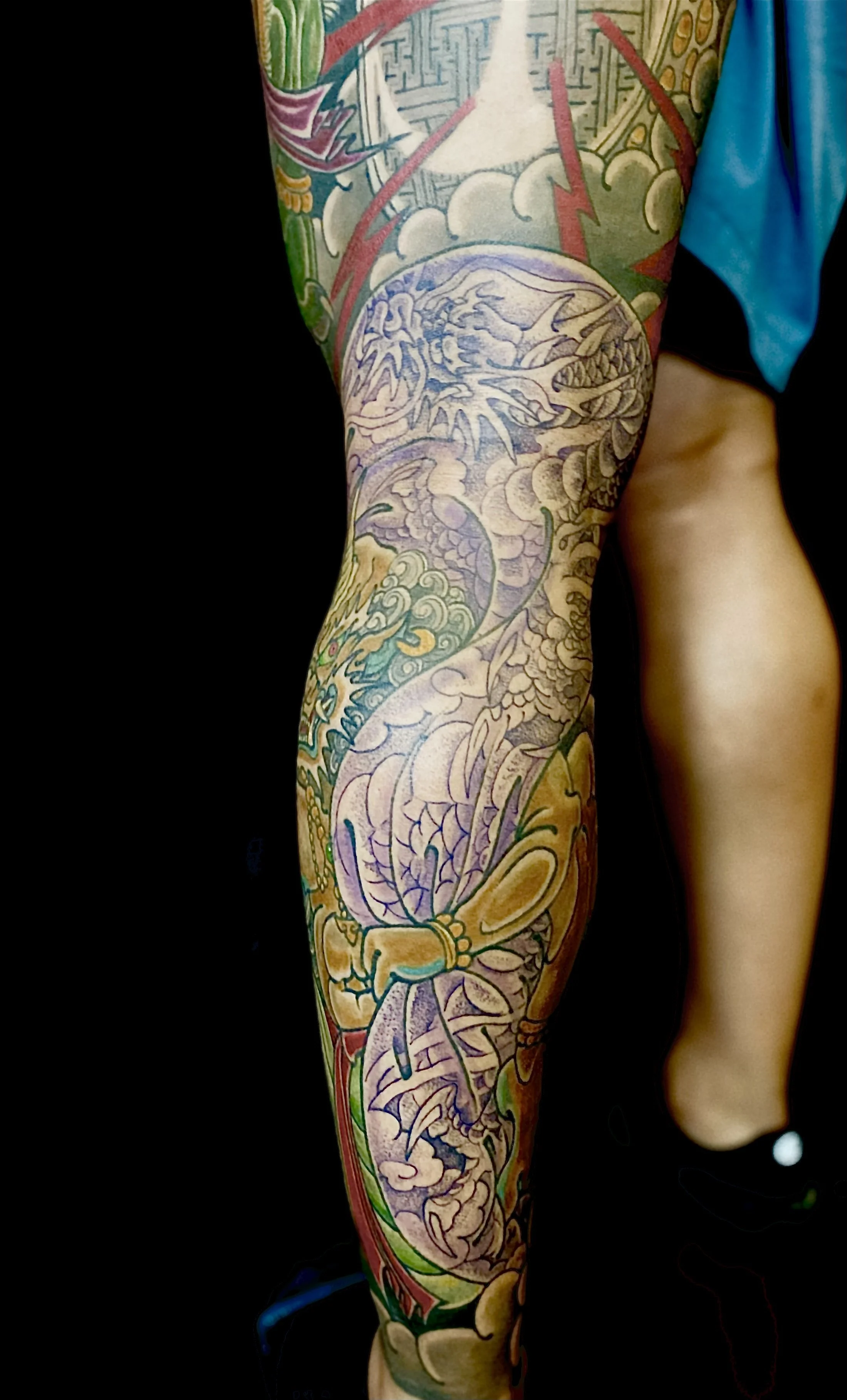 Colorful tattoo sleeve featuring a dragon, a koi fish, and various traditional Japanese motifs.
