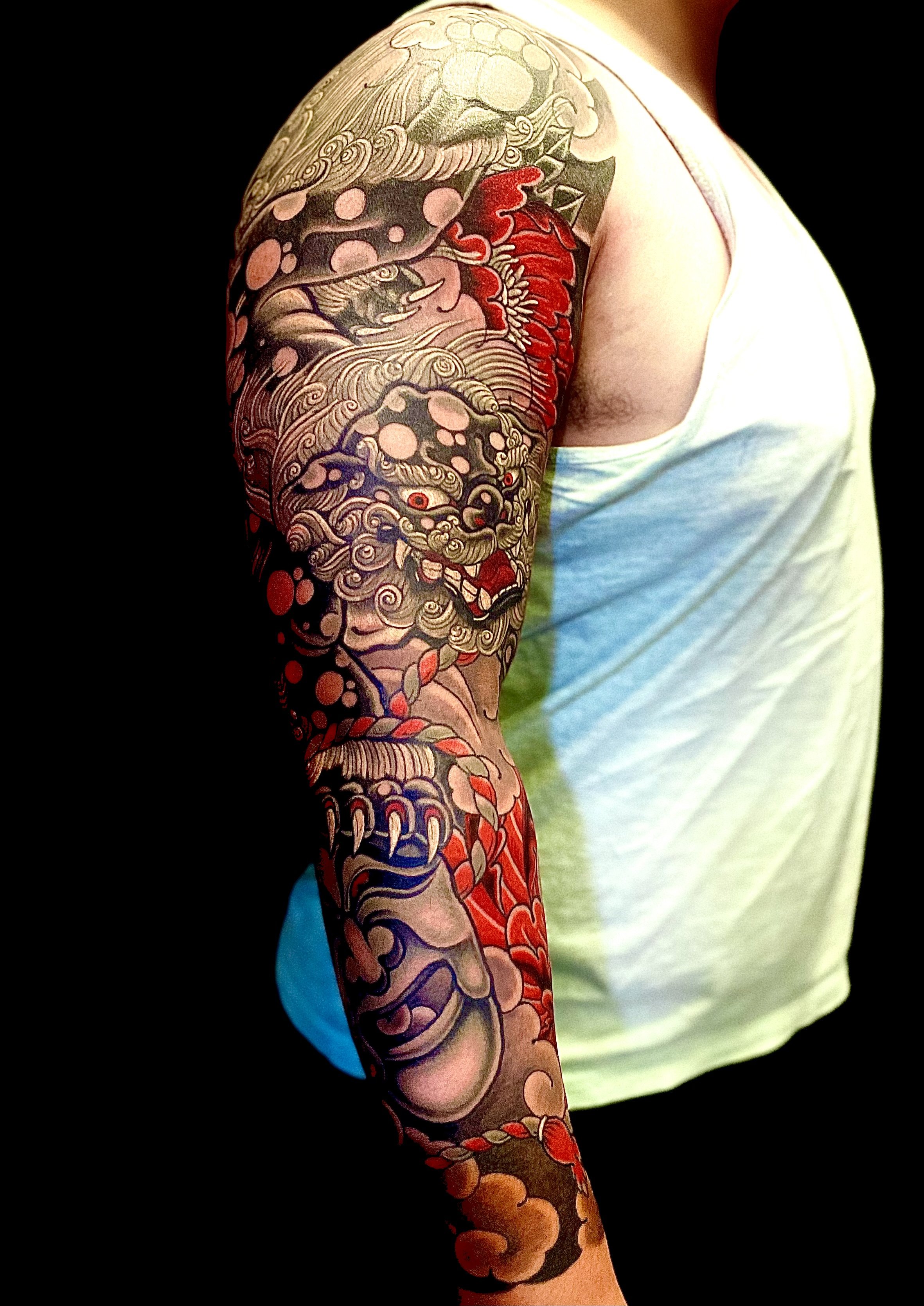 Colorful Japanese-style tattoo sleeve featuring mythical creatures and intricate patterns on a person's arm.