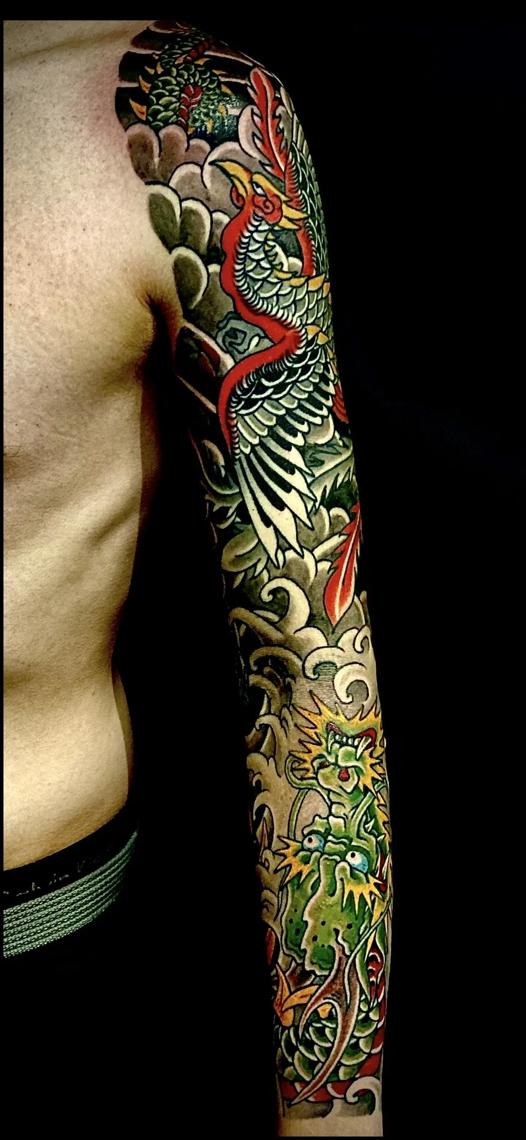 Tattoo of a colorful dragon on the person's arm with swirling clouds and flames.