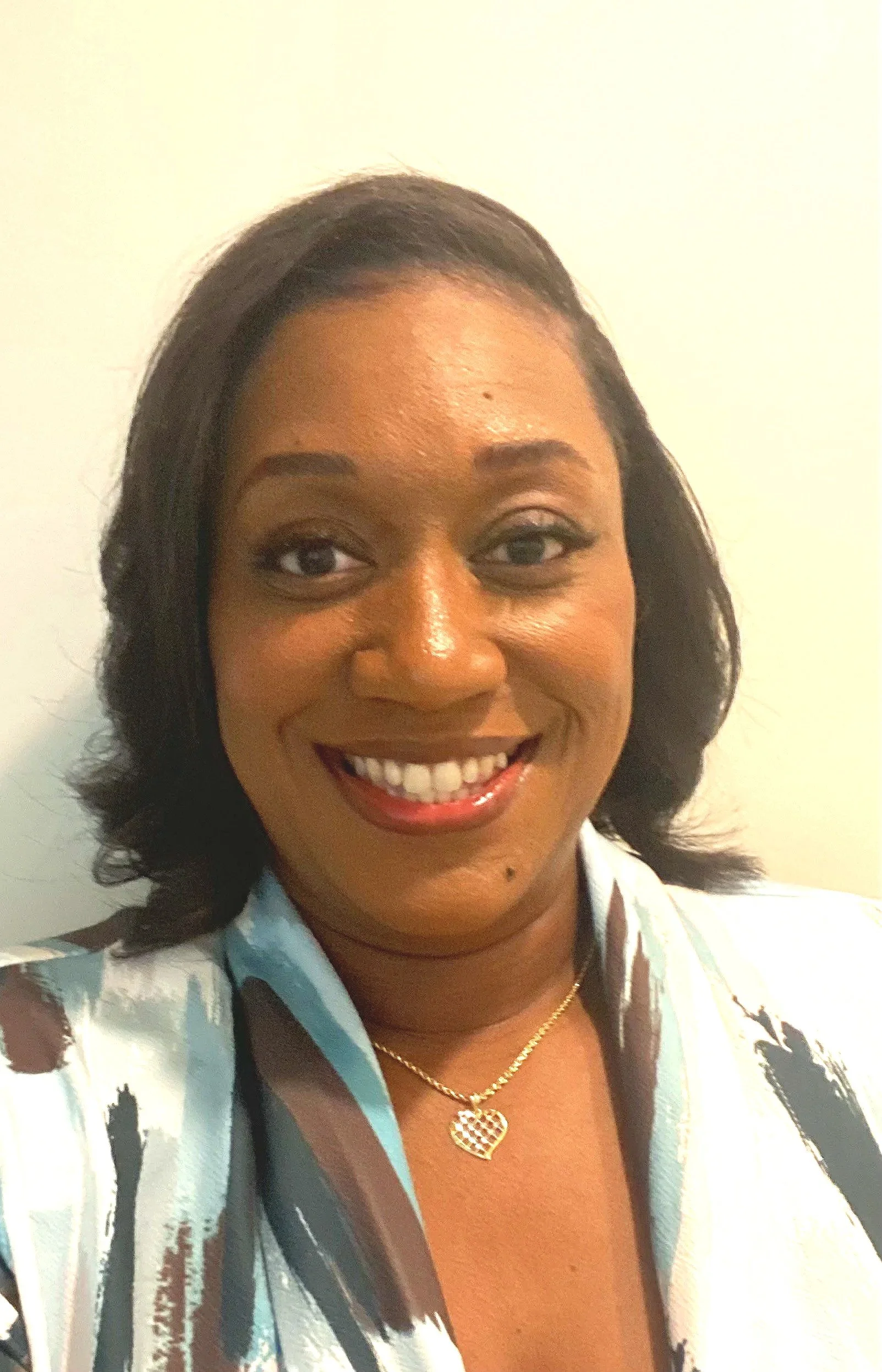 Close-up of a woman with straight black hair, wearing a black top and necklace, with soft makeup and neutral expression.