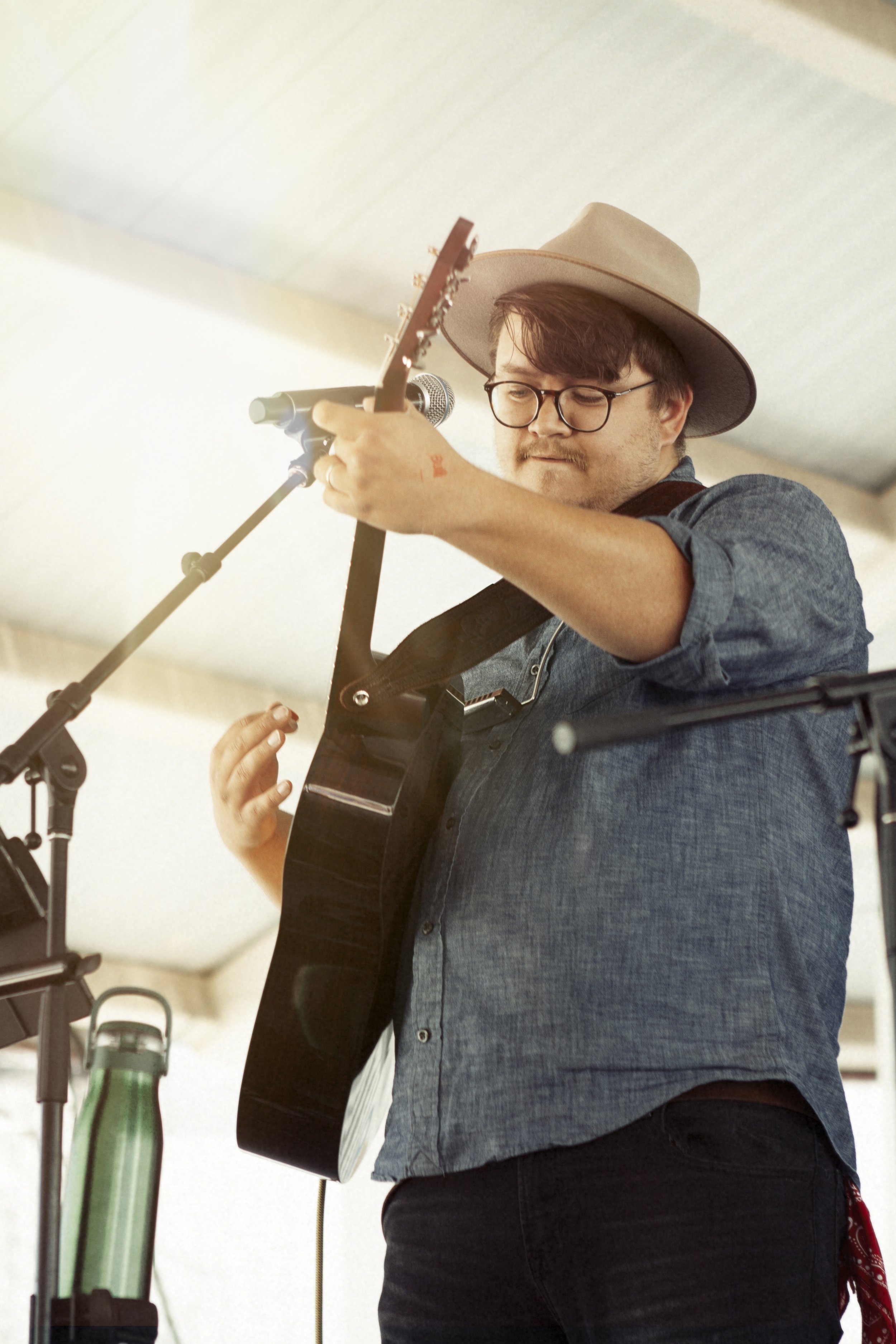 Person wearing a hat playing guitar on stage