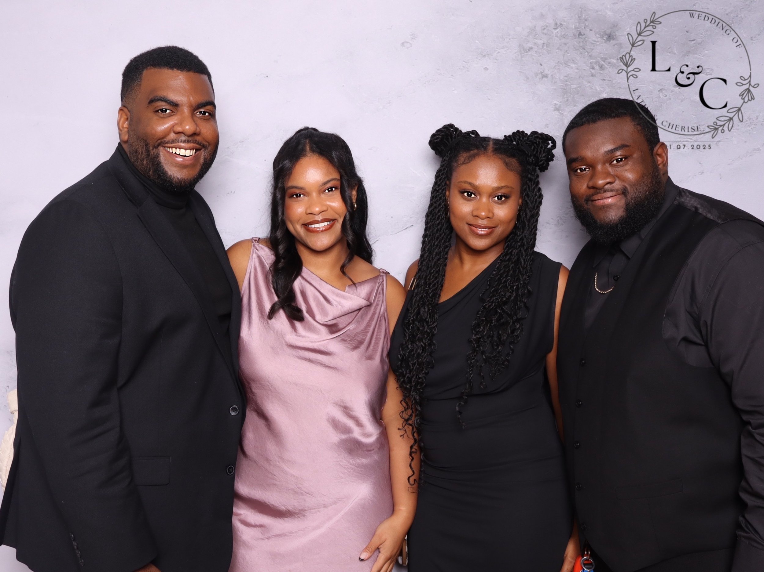 Group of four people dressed formally, smiling, at a wedding celebration with a light gray background and a logo that reads "L & C" and "Wedding of" with names and date.
