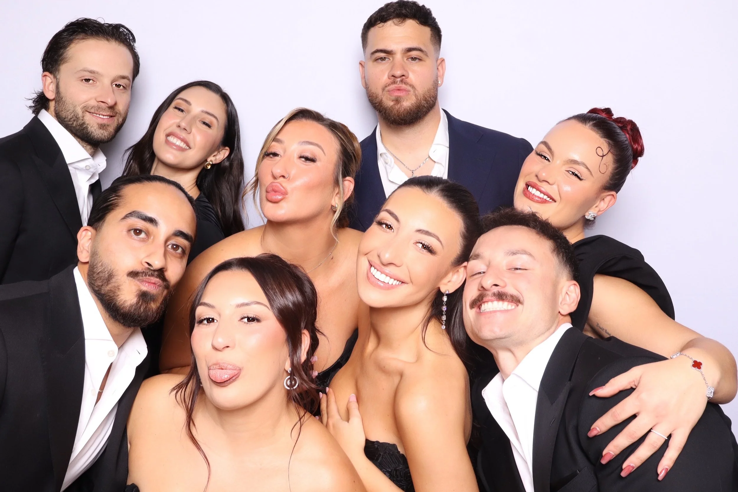 Group of people dressed in formal attire taking a selfie together at a party or event.