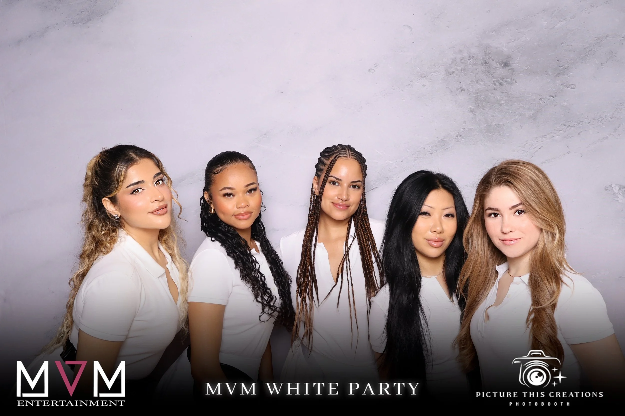 Five women standing side by side, wearing white shirts, posing for a photo at a white party, with branding for MVM Entertainment and Picture This Creations Photobooth.