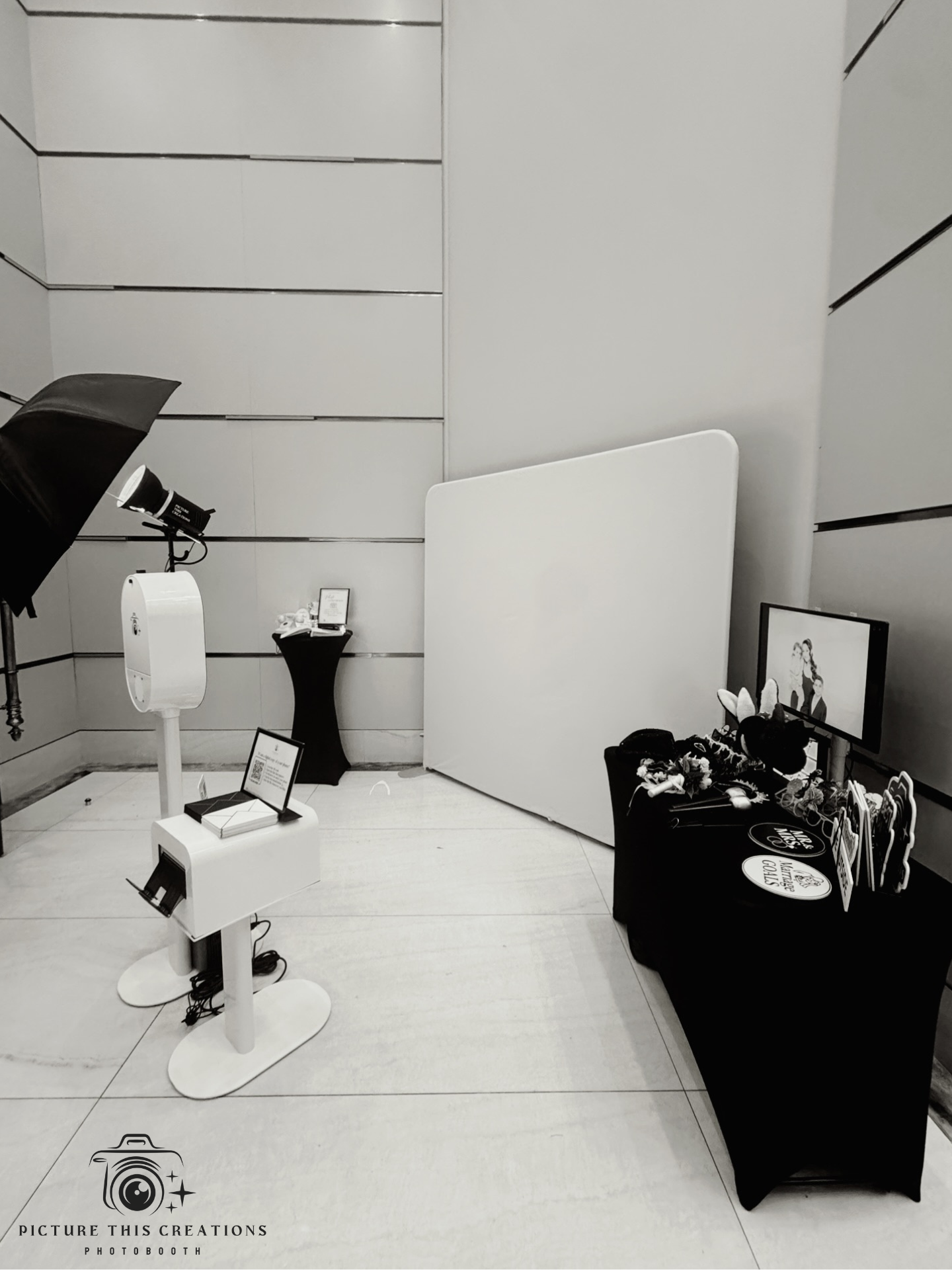 Photo of a photo booth setup with a backdrop, monitor, flowers, and decorations.