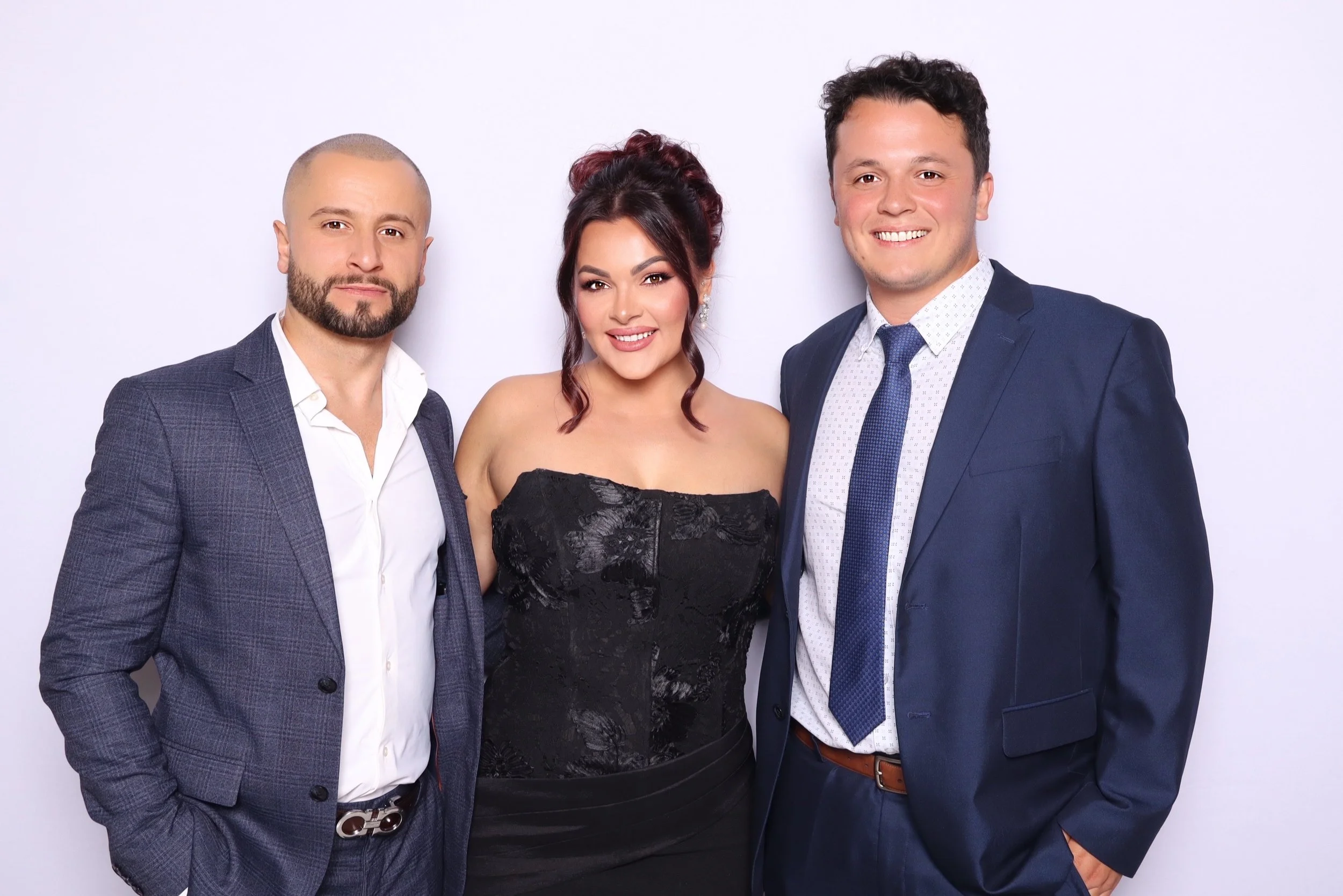 Three people in formal attire posing together against a plain white background.