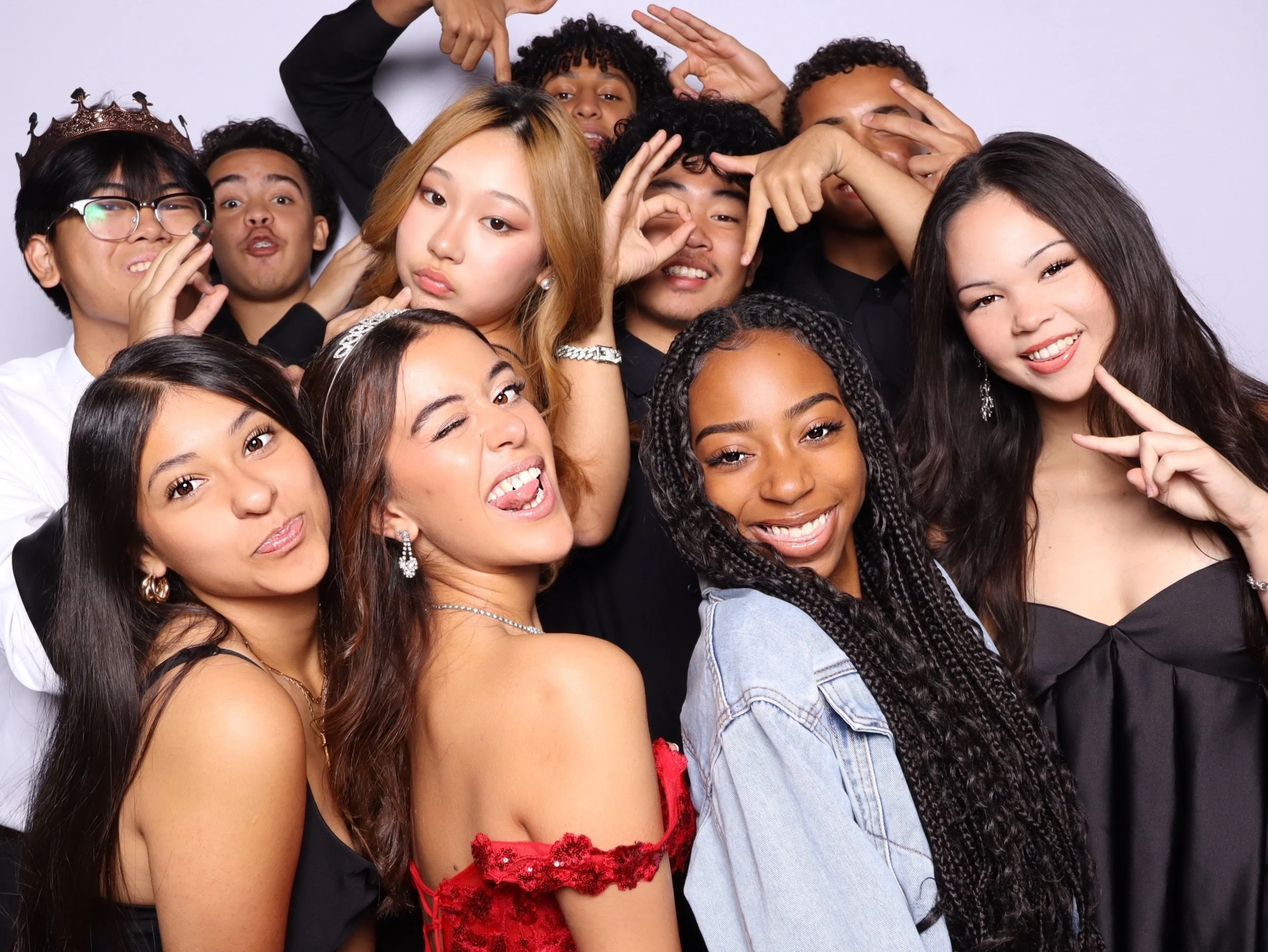 Group of diverse young people posing for a photo together, some making playful gestures, smiling, and showing expressions of fun and friendship.