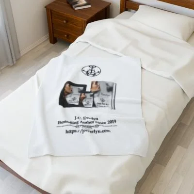 Bed with a white blanket displaying a printed book cover, author name, and website, in a bedroom with a wooden nightstand.