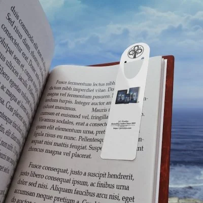 Open book with a white electronic device attached to a page, overlooking the ocean on a cloudy day.