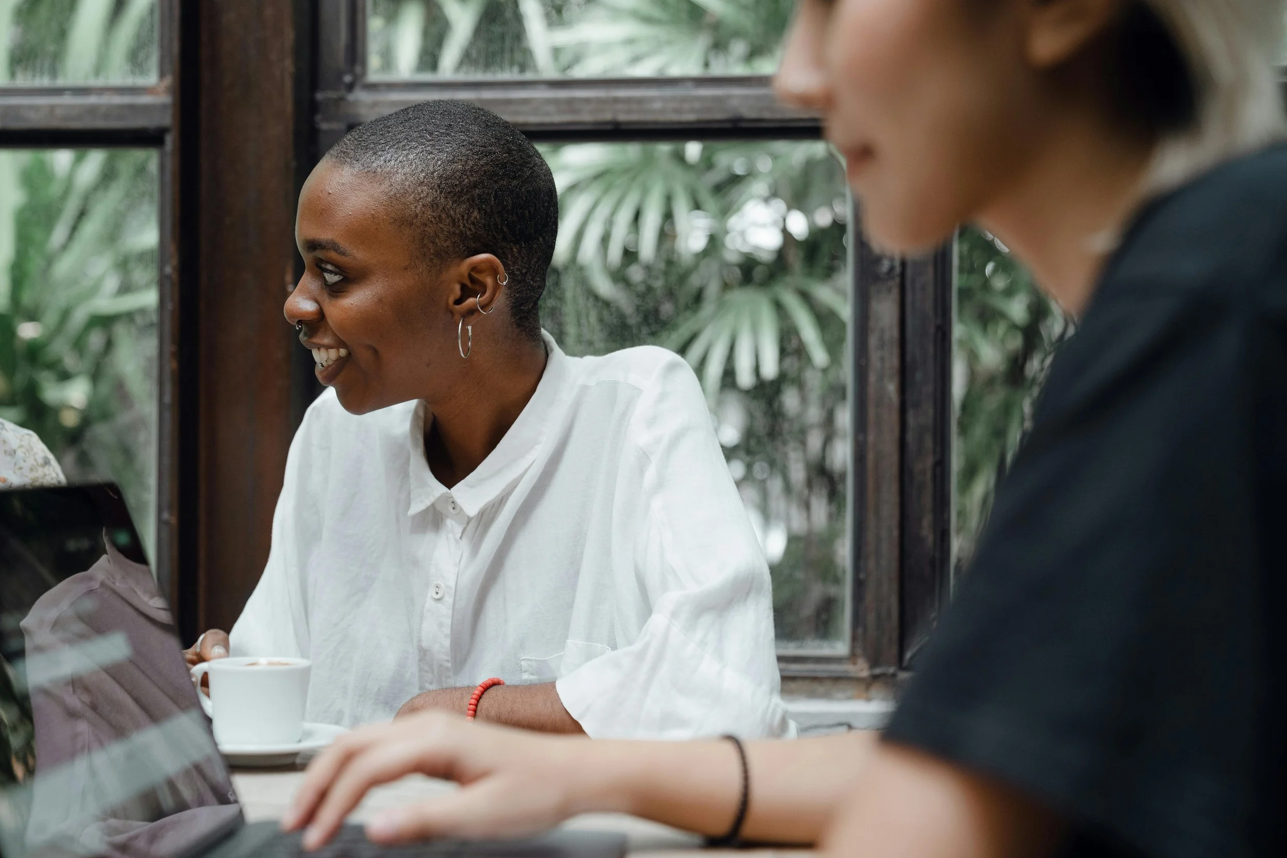 Woman smiling and engaged in conversation over coffee, representing the relational confidence that comes from boundaries work