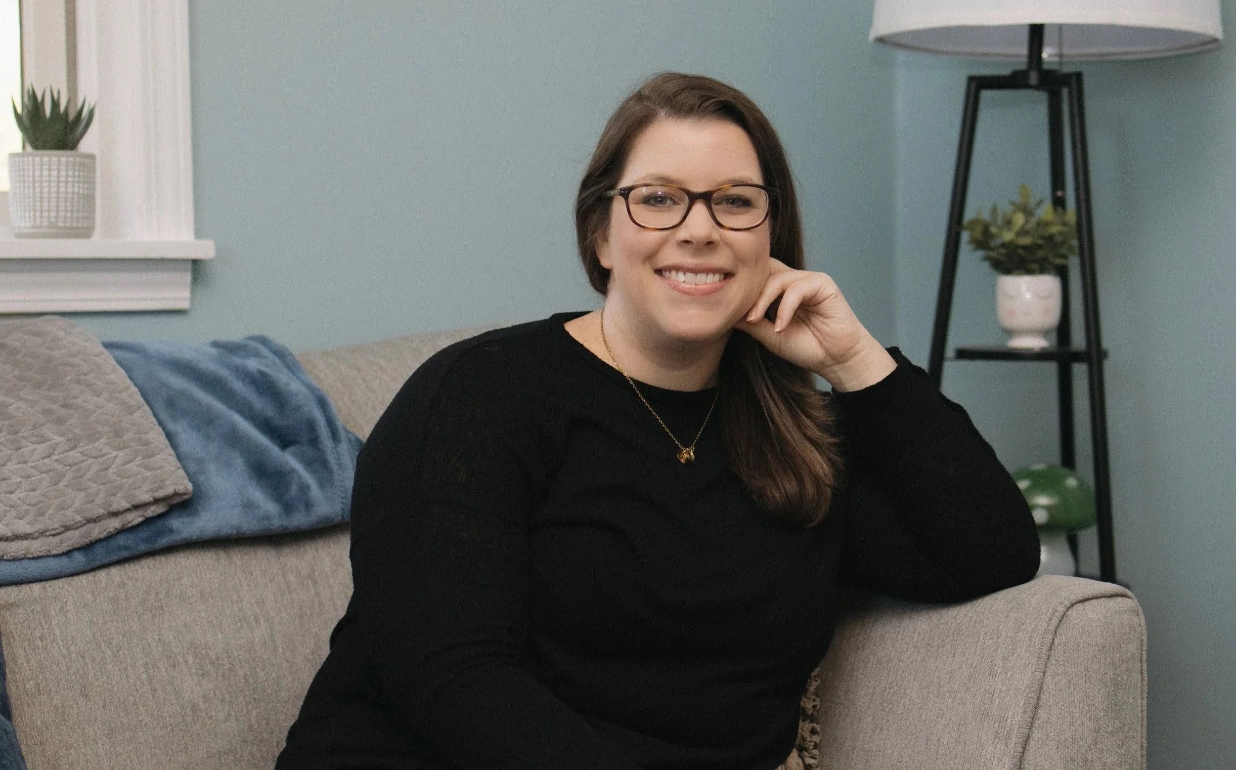 Erin Reddinger, trauma-informed therapist, sitting on therapy couch in her office and smiling