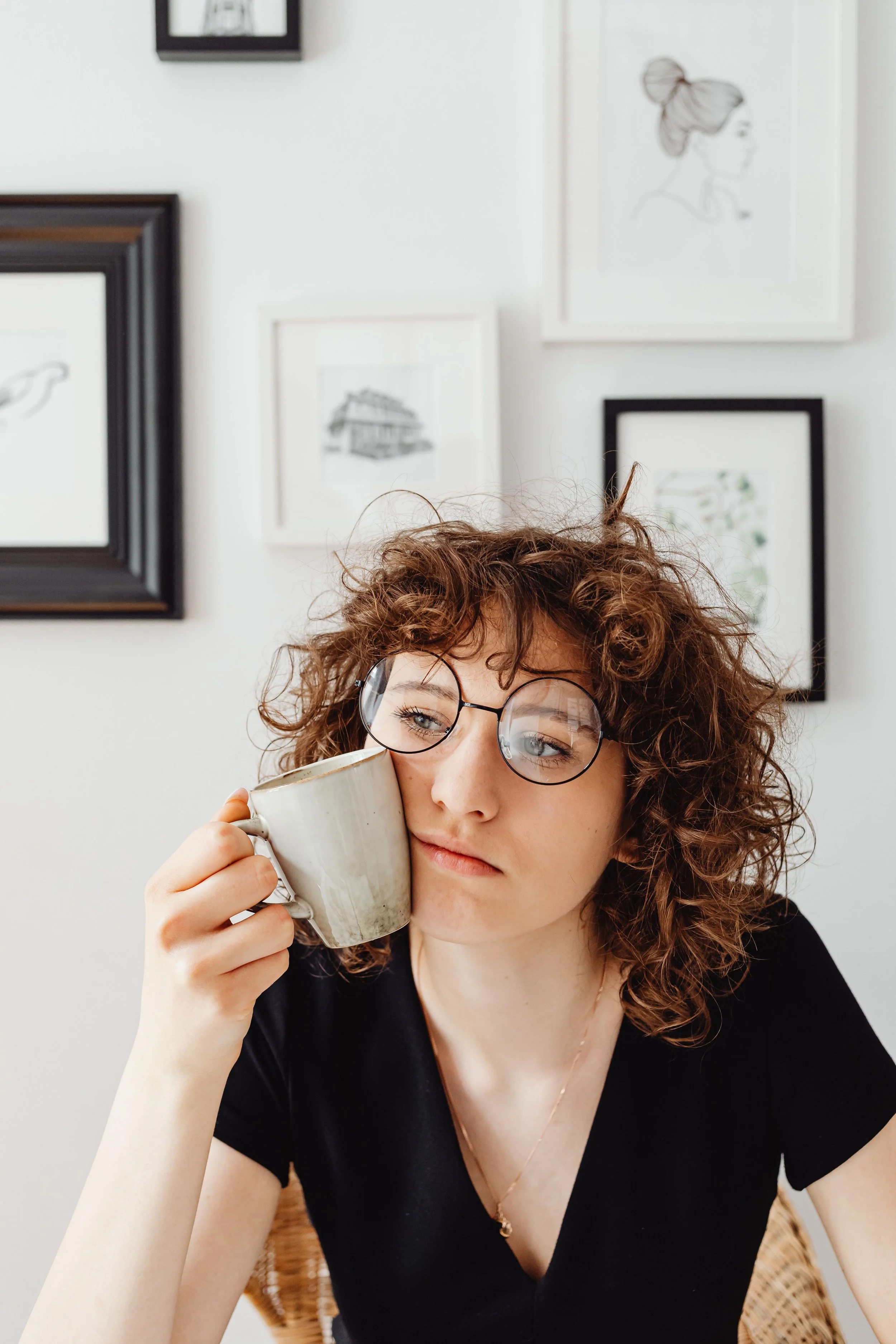 Woman sitting alone holding a mug and looking inward, representing the internal conflict experienced by women working through the fawn response and people-pleasing patterns in therapy
