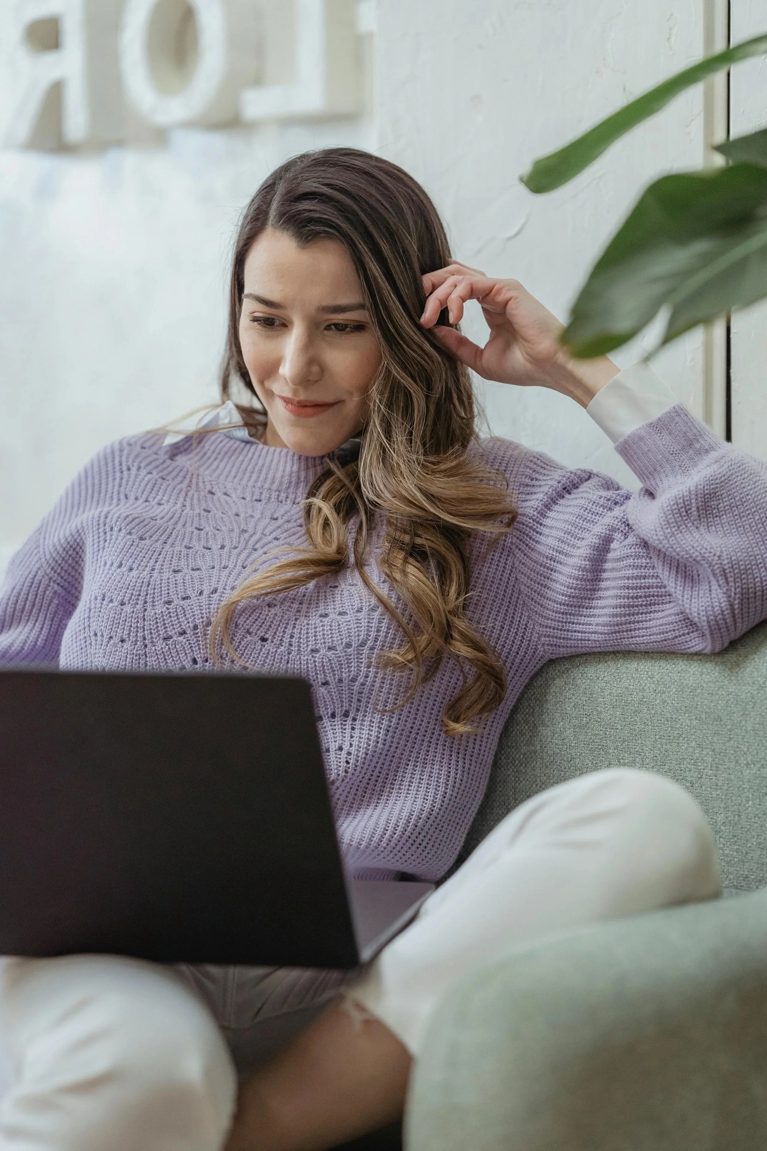 Woman working on a laptop while sitting on a couch in a relaxed home environment