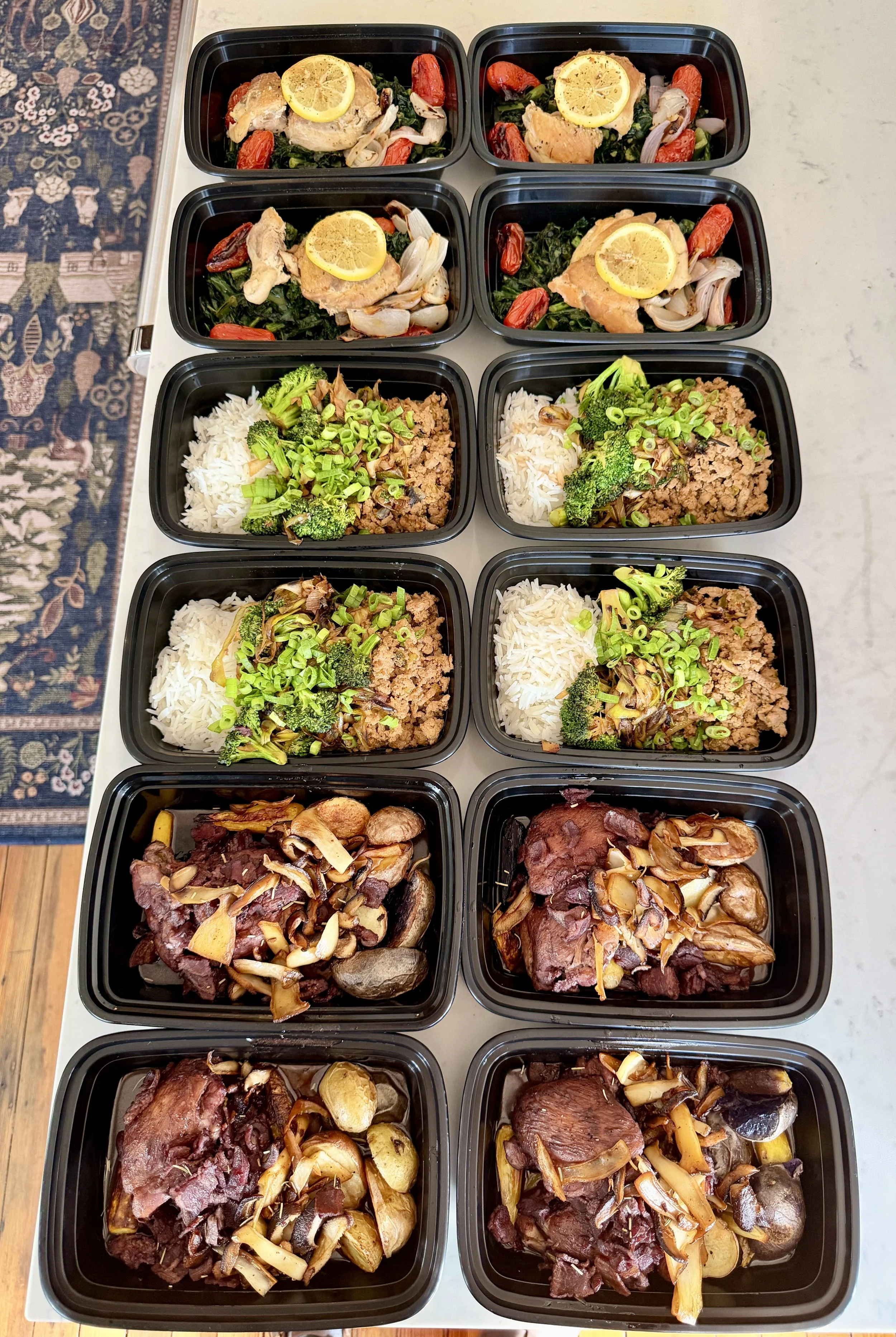 Prepared multi-layered meal containers with chicken, beef, rice, vegetables, and mushrooms.