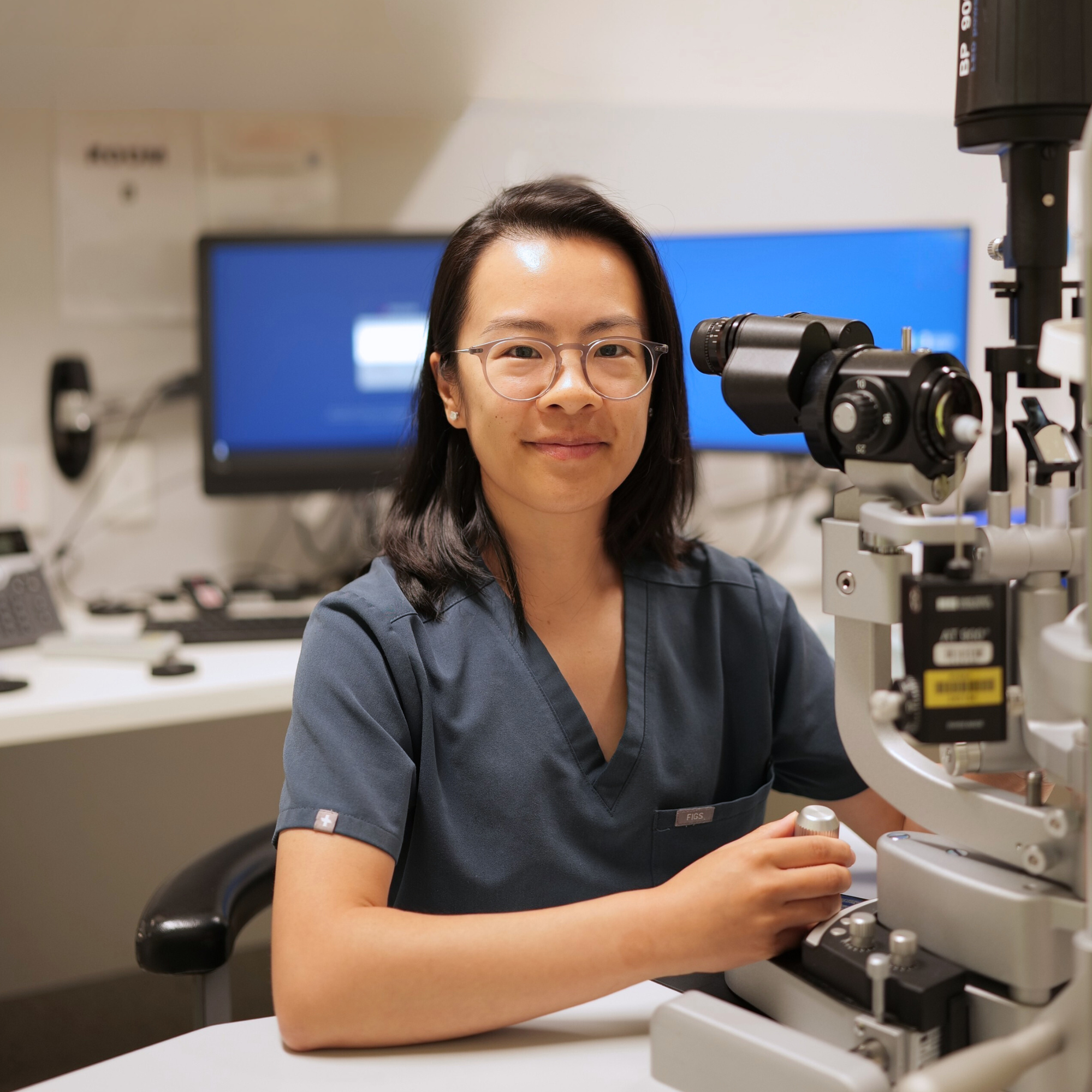 A scientist with glasses operating a microscope in a laboratory.