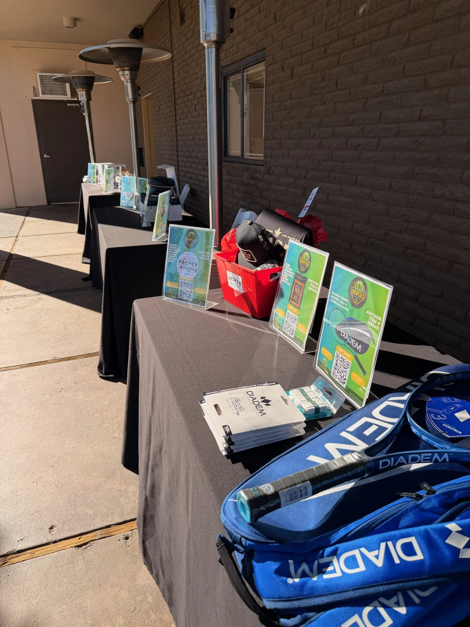 Outdoor display of tables with sports equipment and promotional signs.