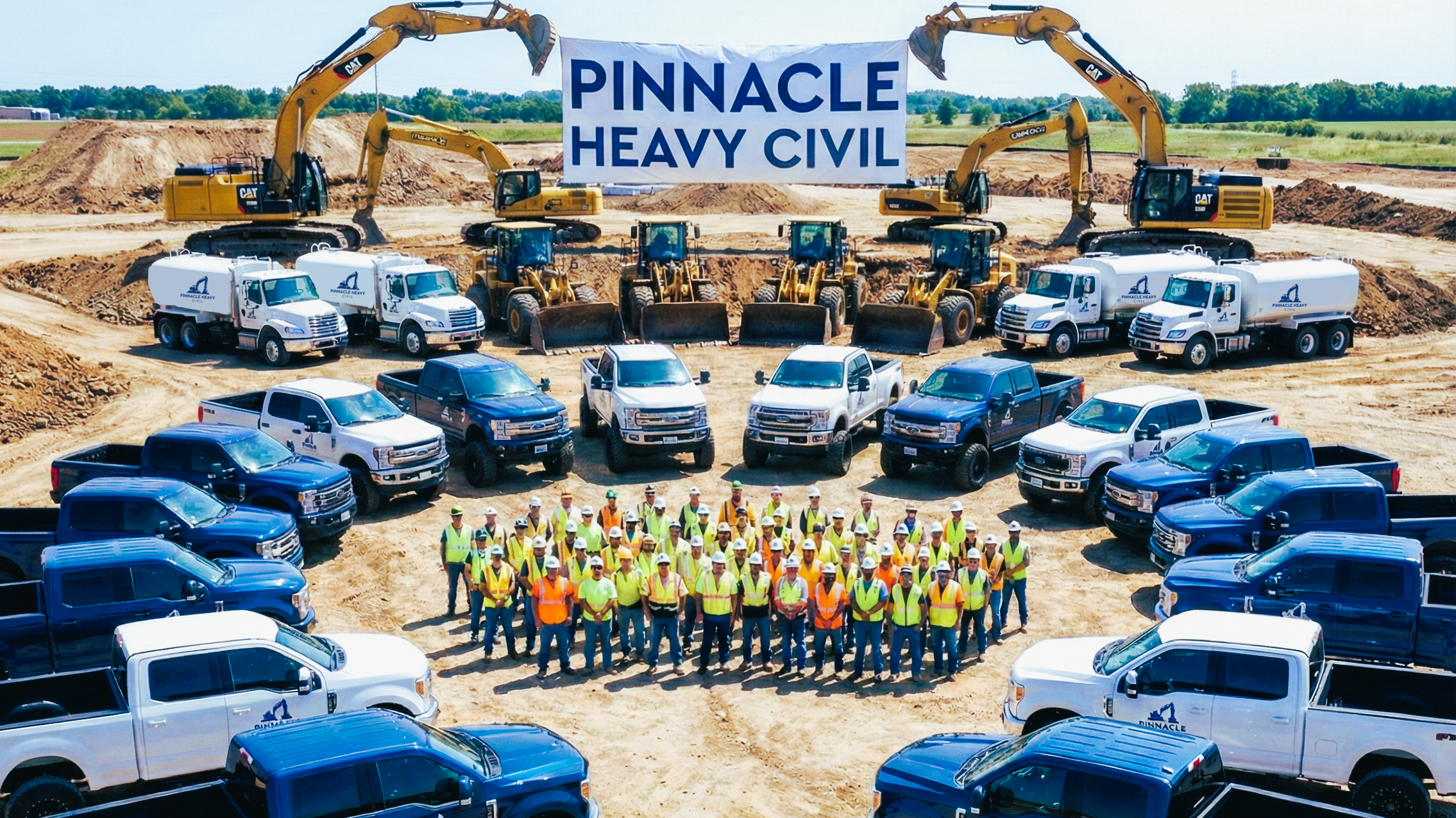 Construction site with heavy machinery, trucks, and a group of workers in safety gear, holding a banner that reads "Pinnacle Heavy Civil."