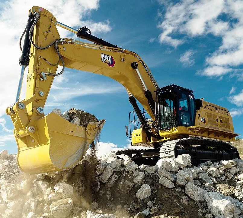 Rock excavation in phoenix, az Caterpillar excavator digging into rocks on a construction site under a partly cloudy sky.