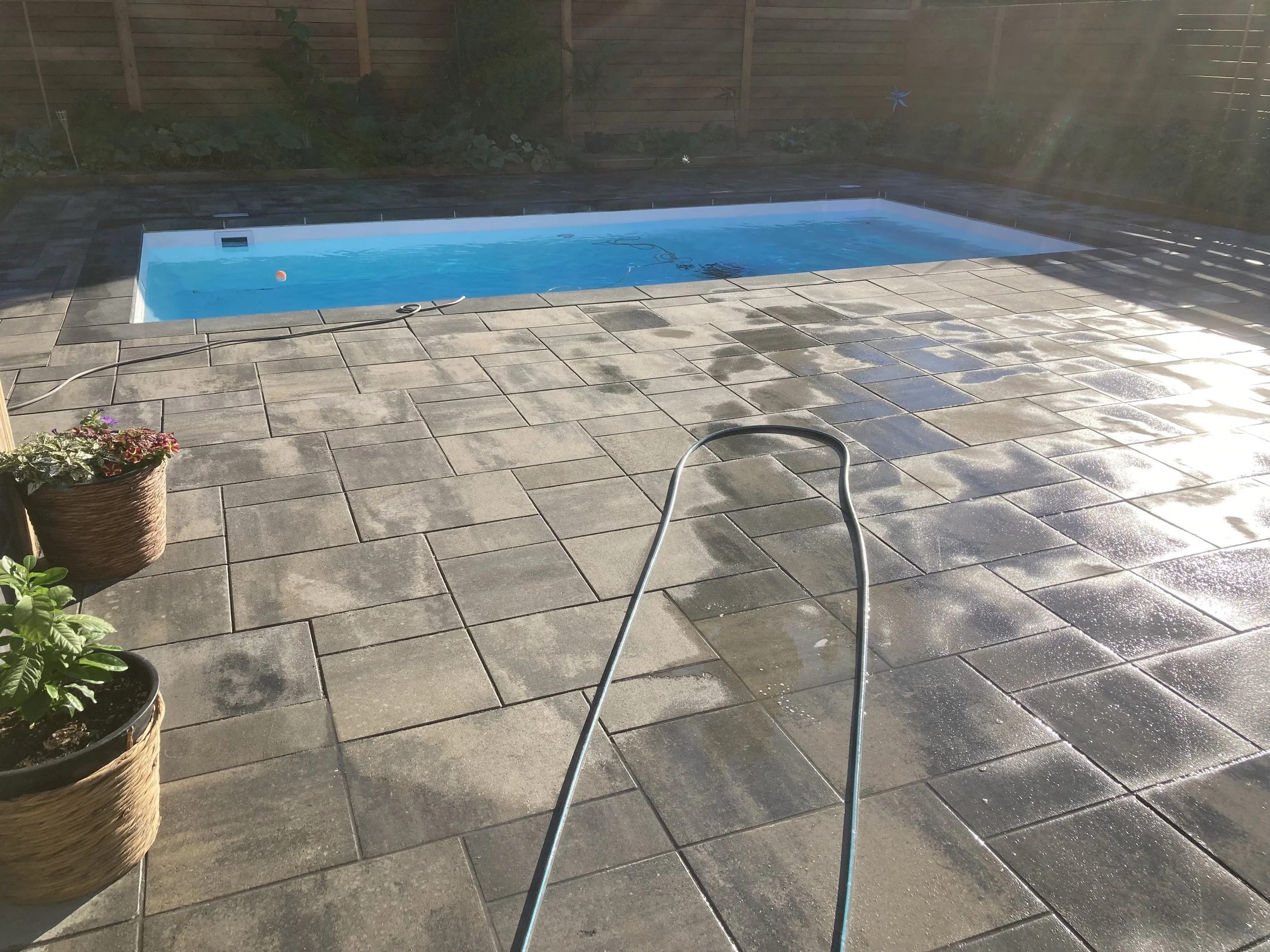 Backyard swimming pool with stone patio and potted plants