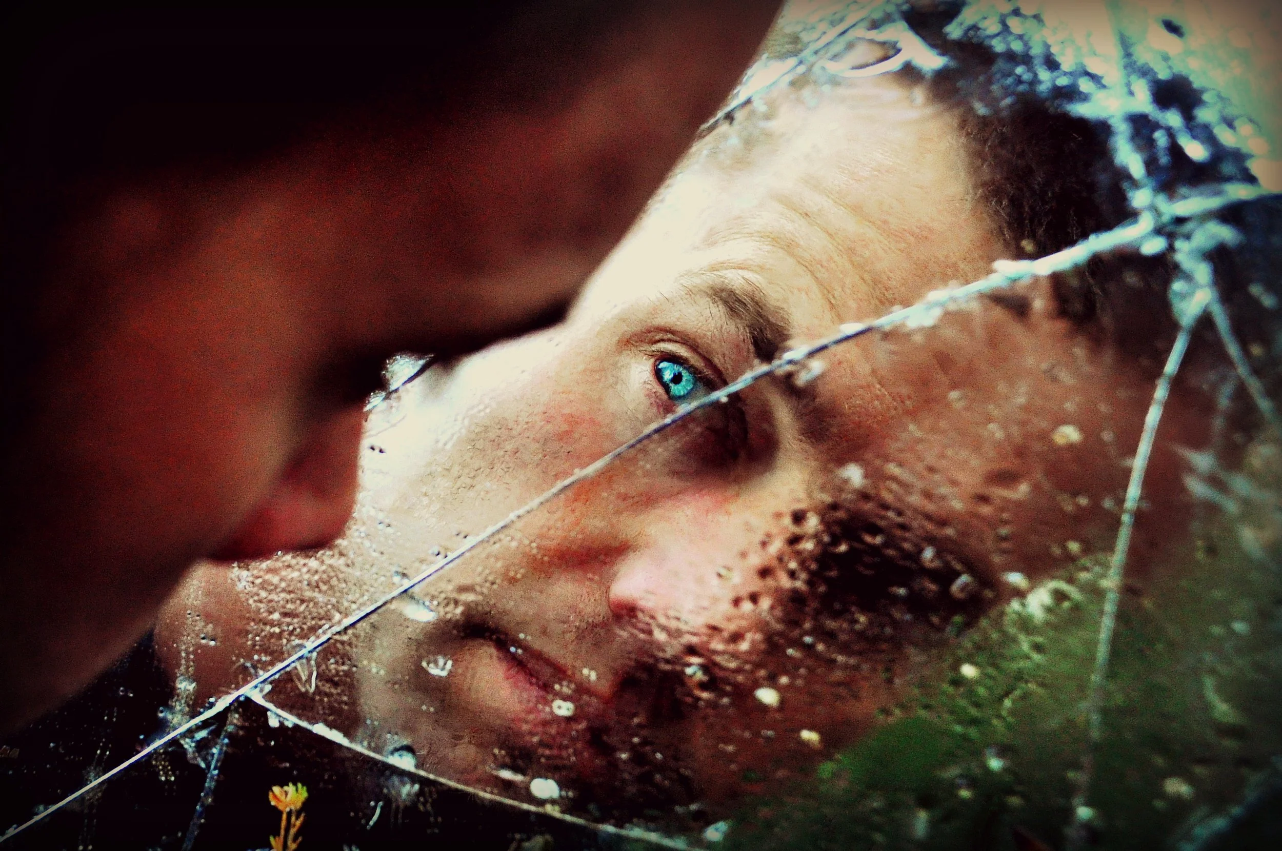man lookin into cracked mirror