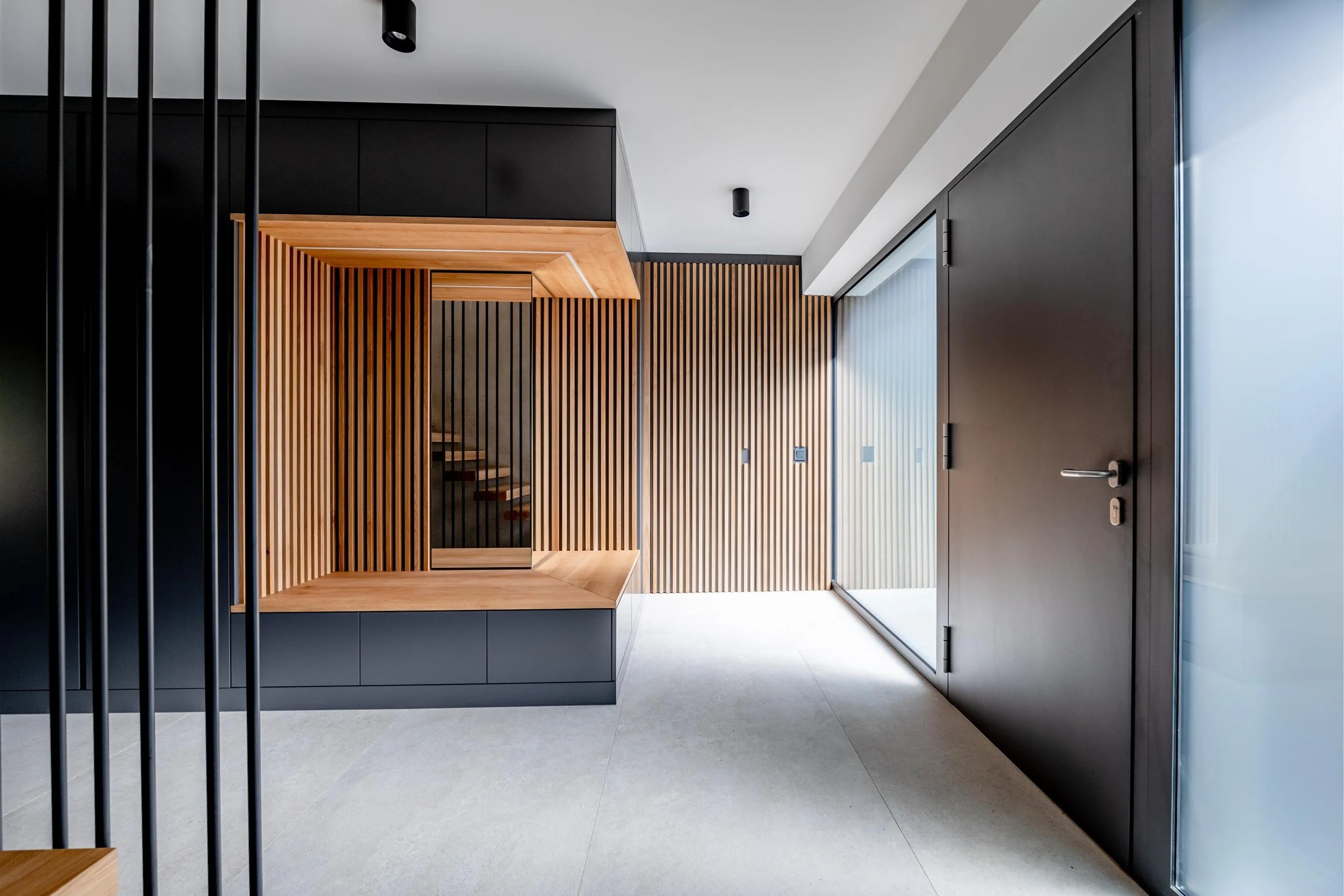 Intérieur moderne avec portes en bois et murs en panneaux de bois vertical. Sol en carrelage clair et plafond blanc avec detection de mouvement. Fenêtre en vitres teintées ou translucides.