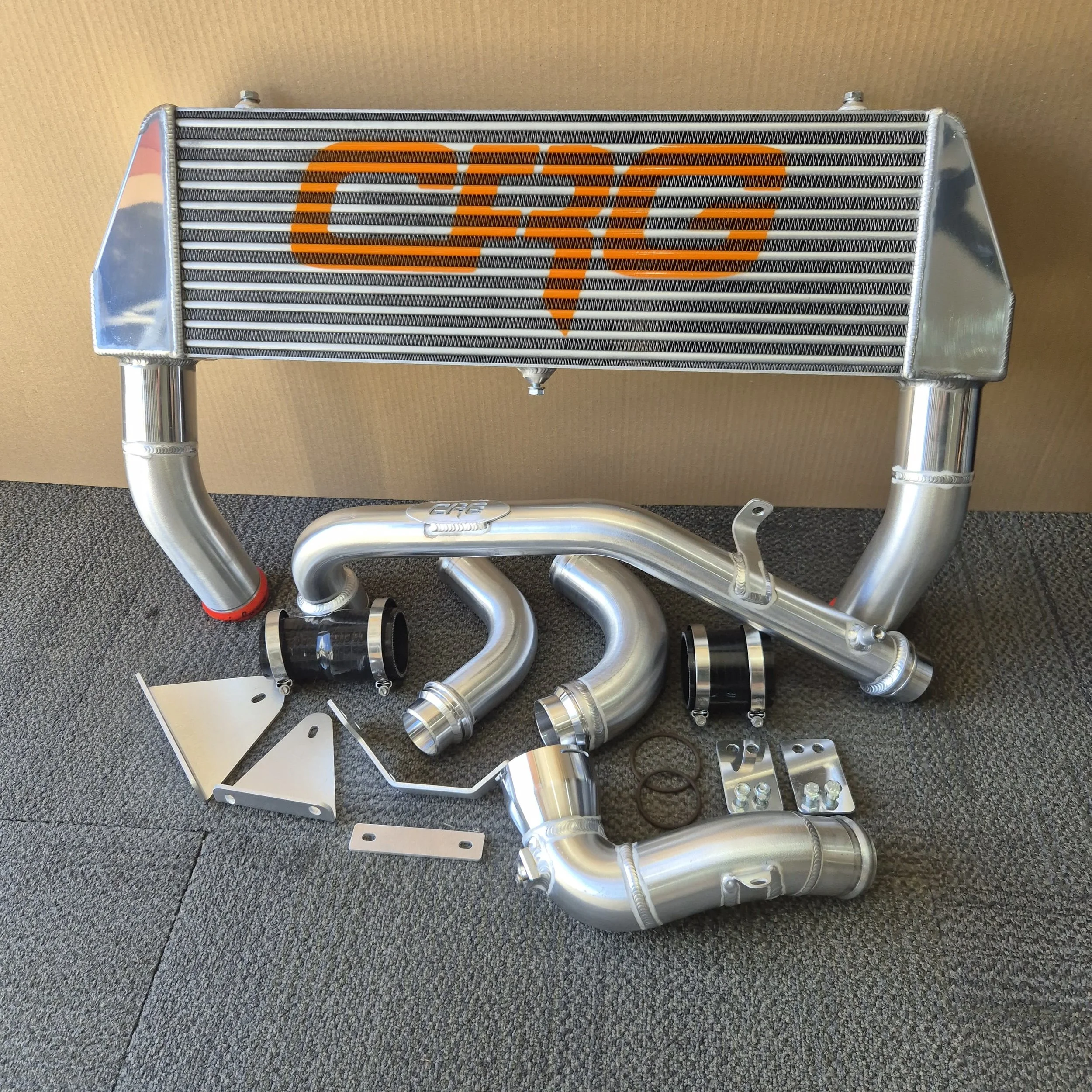 An aftermarket automotive intercooler with associated piping and mounting brackets