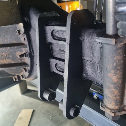 Close-up of a black metal mounting bracket attached to a vehicle chassis.