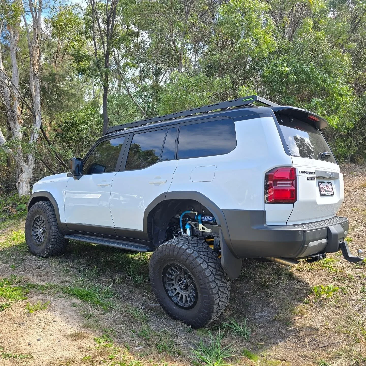 A white off-road vehicle with four wheels parked on uneven ground 