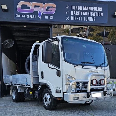 White Isuzu flatbed truck parked in front of CRG