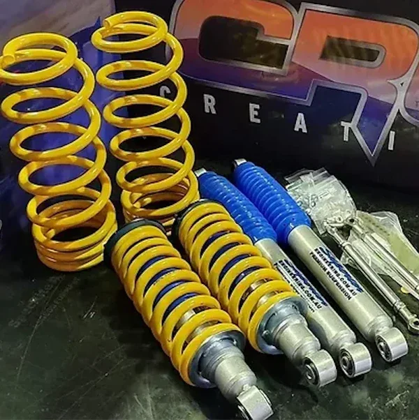 A set of four yellow and blue shock absorbers with coiled springs, along with some small hardware parts 