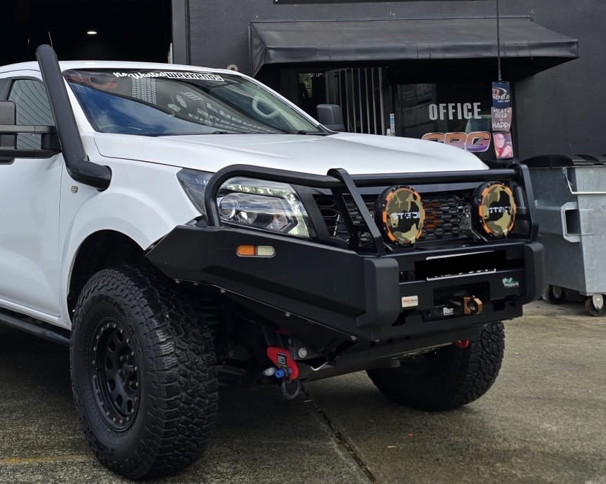 White off-road vehicle with black body armor and large tires, equipped with heavy-duty bumper