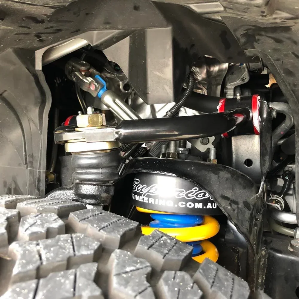 Close-up view of a vehicle suspension system with a coil spring, shock absorber, and various connecting parts, indicating an off-road or racing vehicle.