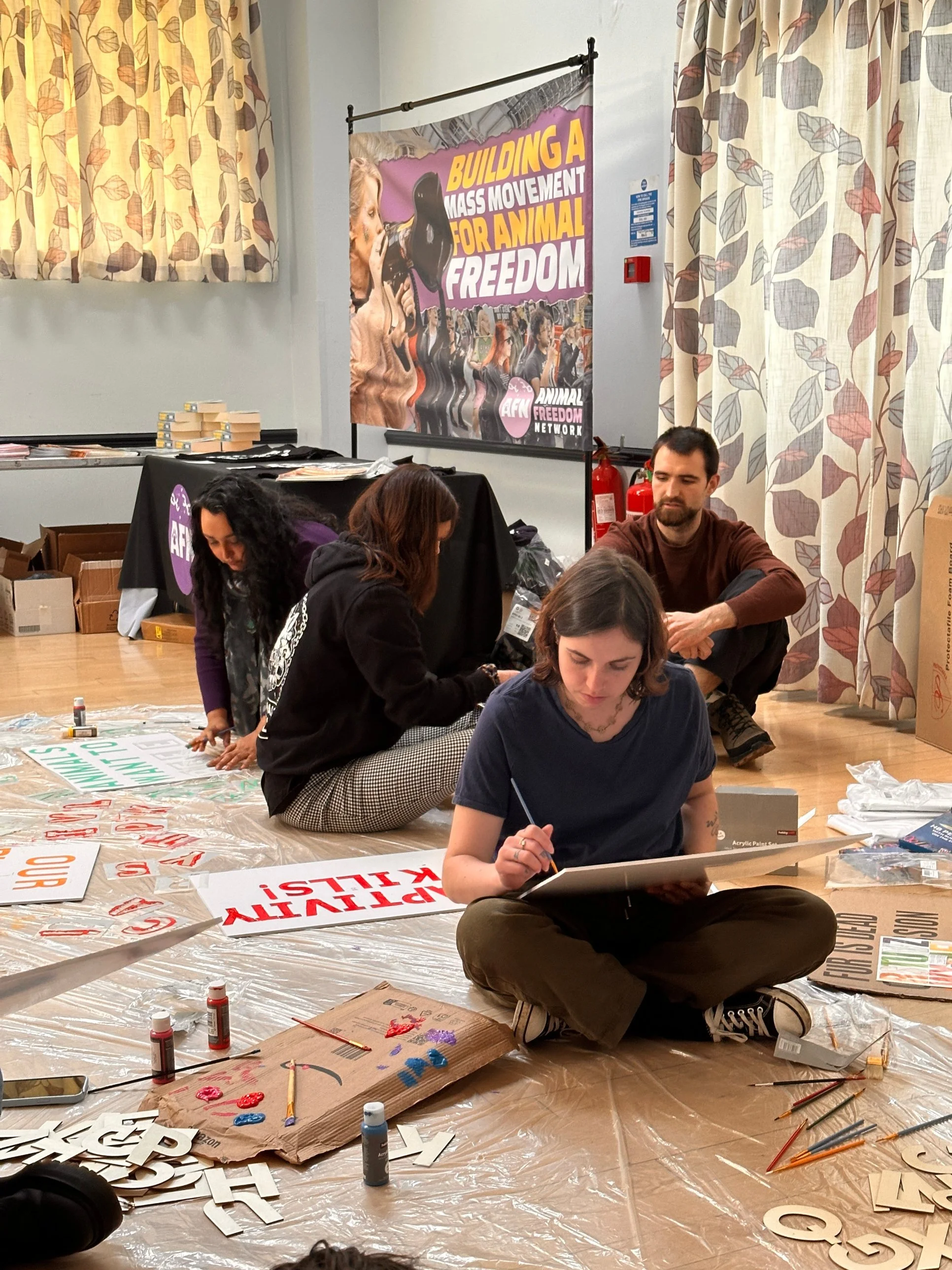 Activists painting placards at a Project Phoenix organising bootcamp, under a banner reading Building a mass movement for animal freedom