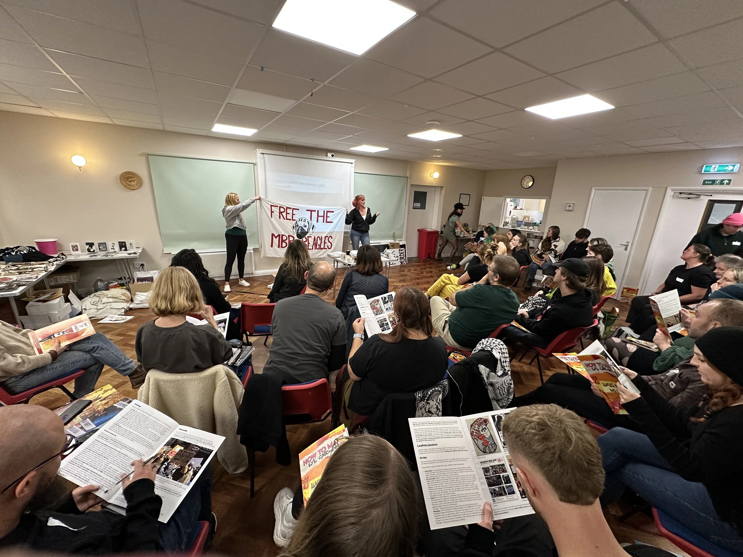 Activists at an Animal Freedom Network training bootcamp, seated in a hall listening to a speaker