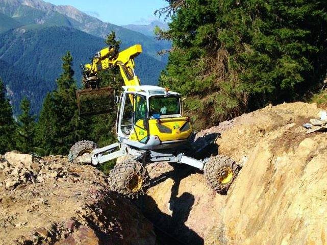 Escavatore ragno giallo su terreno montuoso