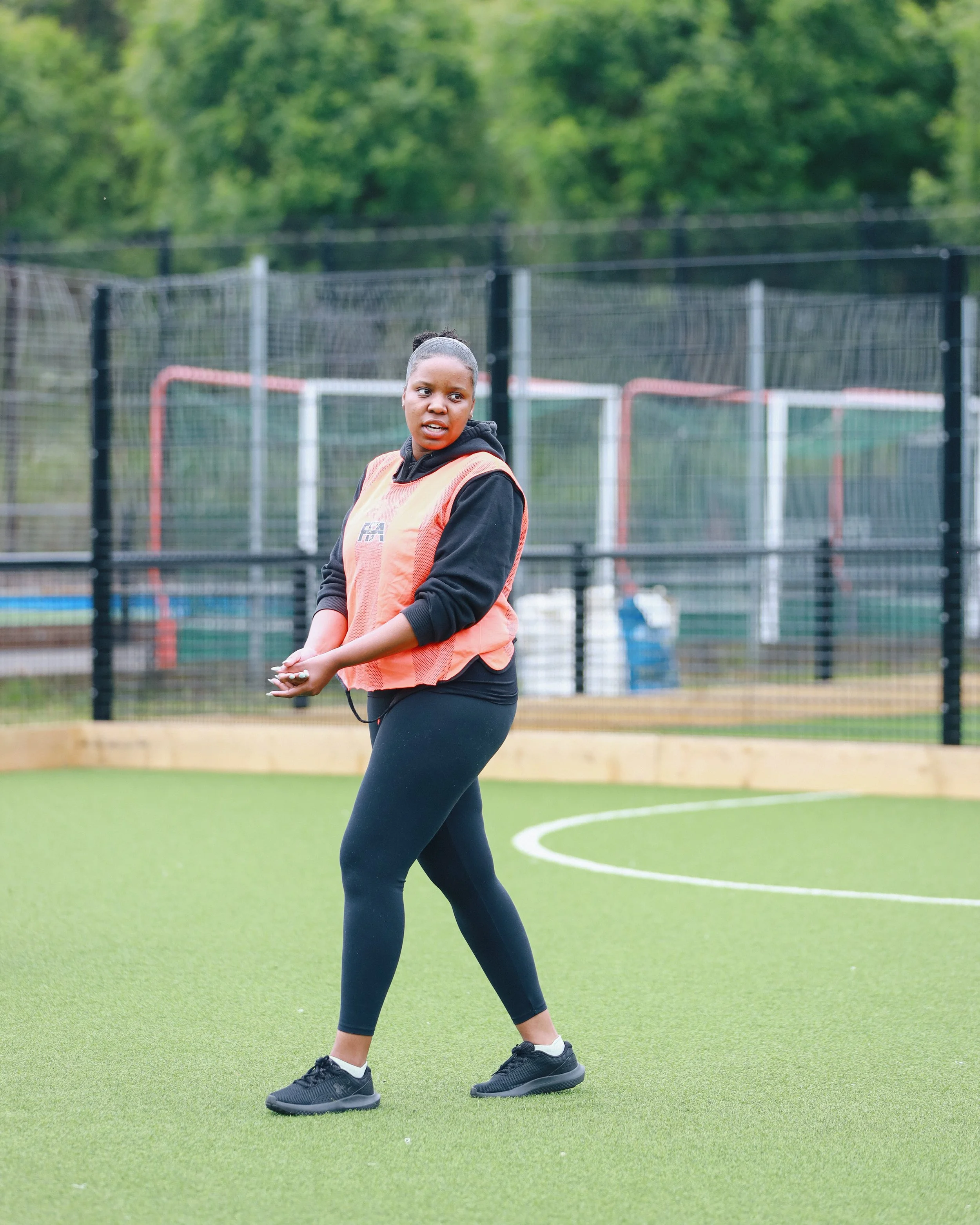 Female soccer player standing on a green artificial turf field during a practice or game.
