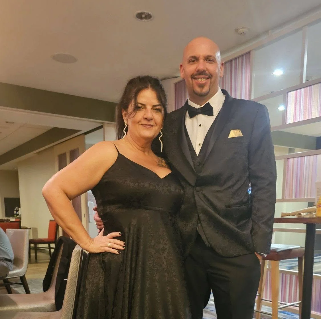 A woman in a black dress and a man in a tuxedo at a formal event.