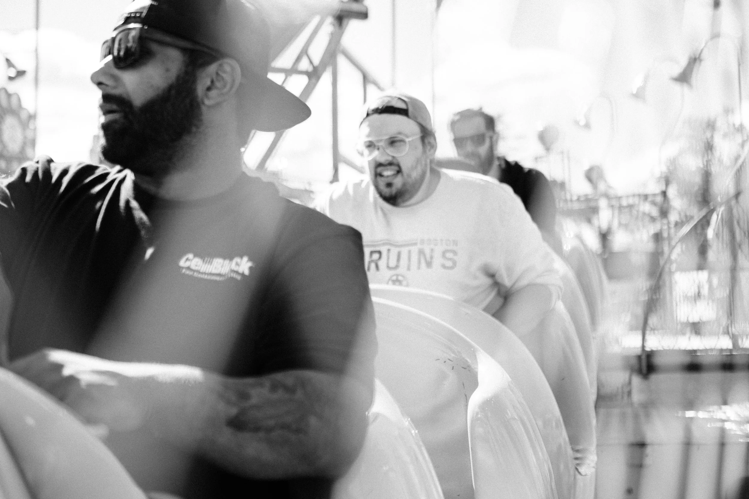 A group of people riding a roller coaster, with some smiling and others focused, in an amusement park on a sunny day.