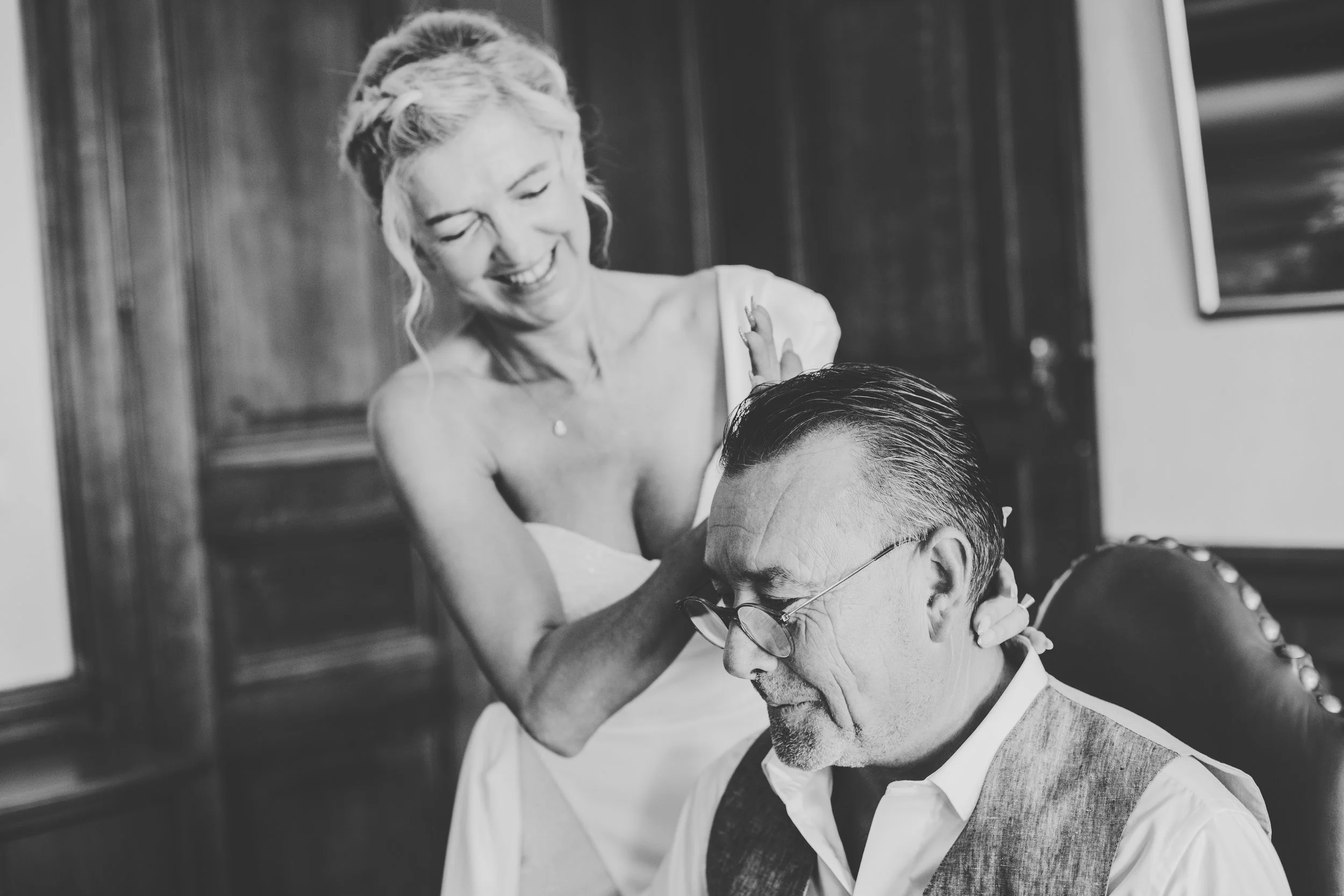 Bride fixing groom's hair while smiling