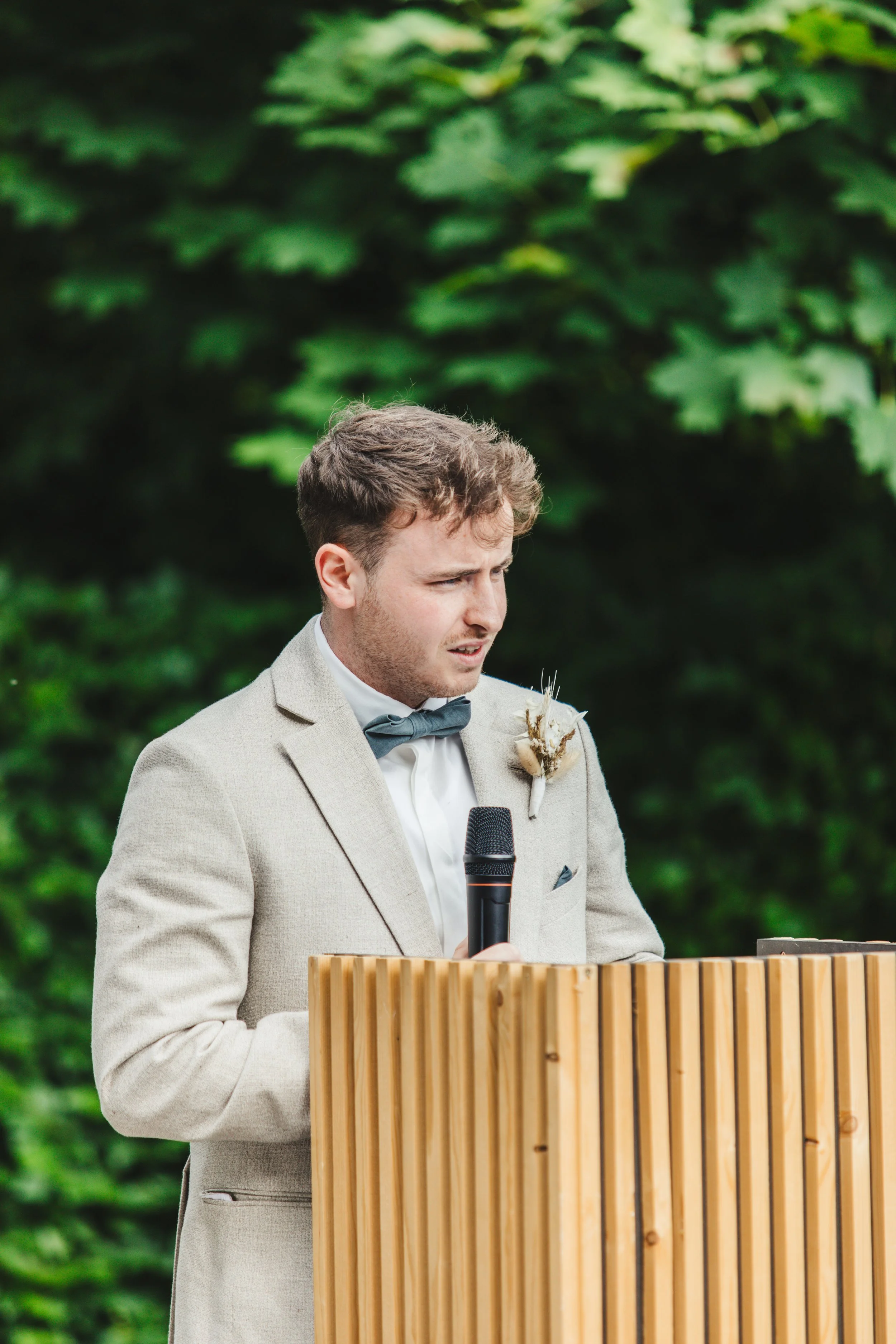 Man in beige suit giving a speech outdoors
