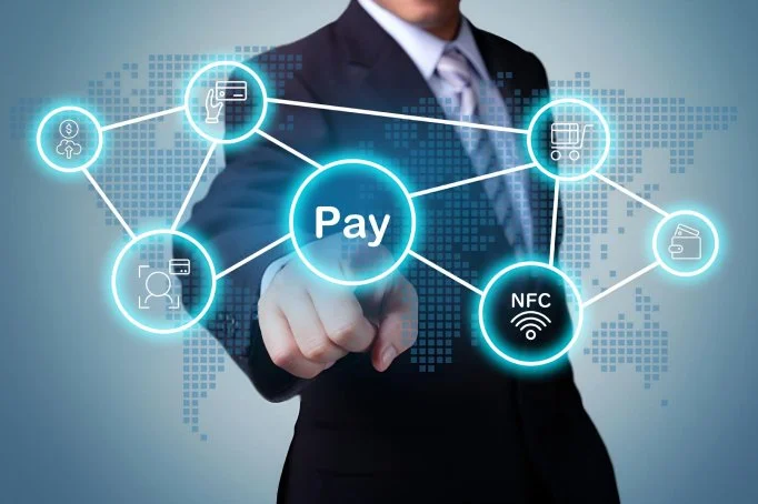 A businessman in a suit interacting with a digital graphic of interconnected icons representing payment methods and NFC technology.