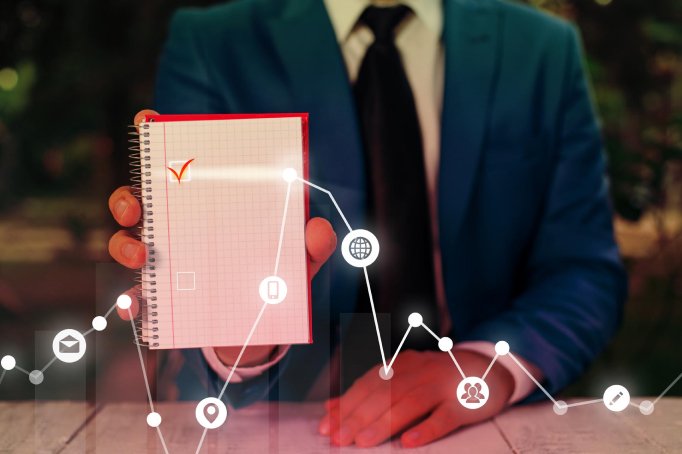 Person in a business suit holding a red and white notepad outdoors, with digital graphs and icons overlaid.