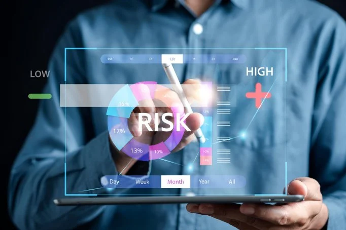A person in a blue shirt interacting with a transparent digital tablet displaying a risk analysis chart and various data metrics related to risk levels.