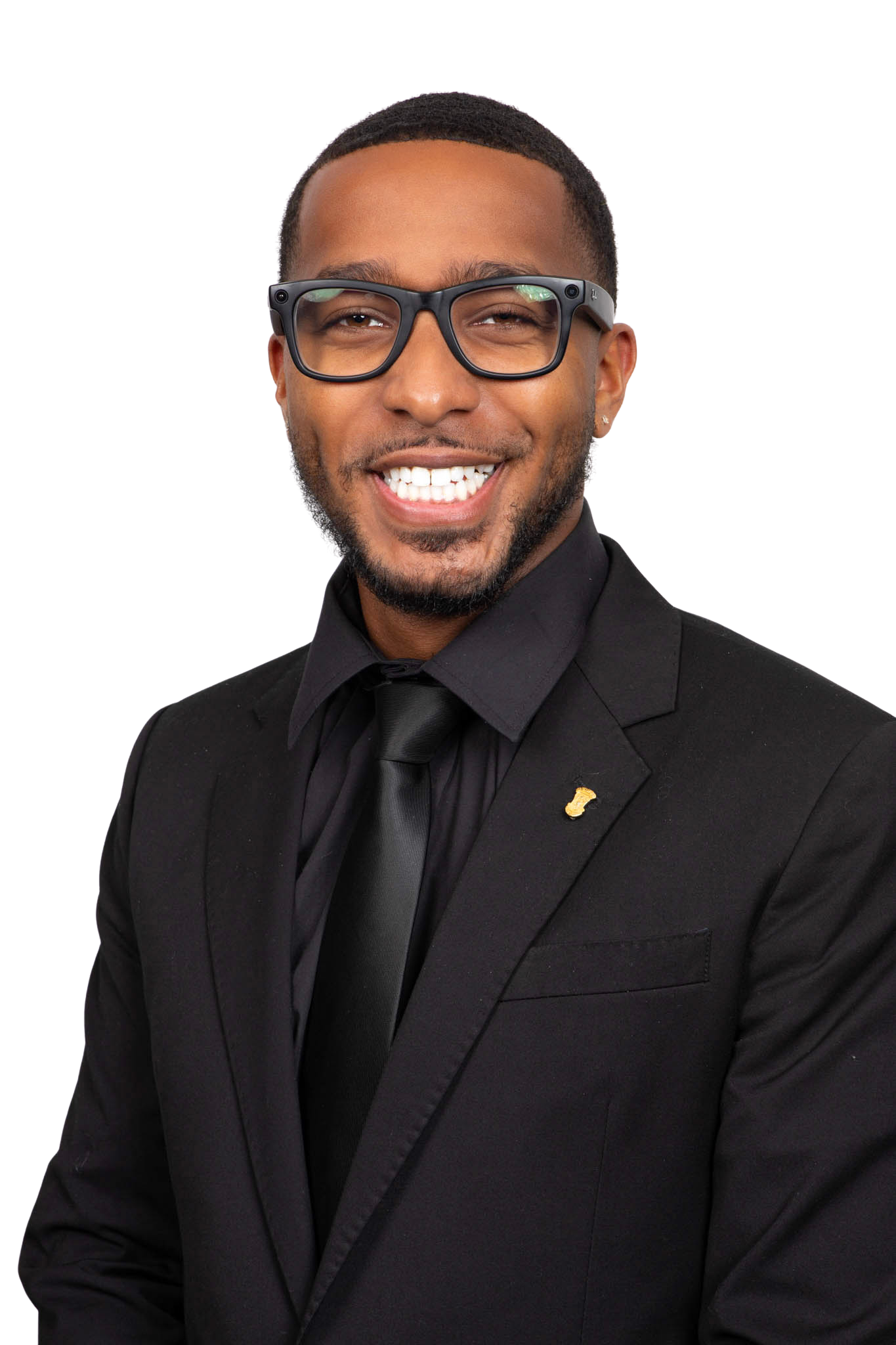 Man wearing glasses, a black suit, black shirt, and tie.