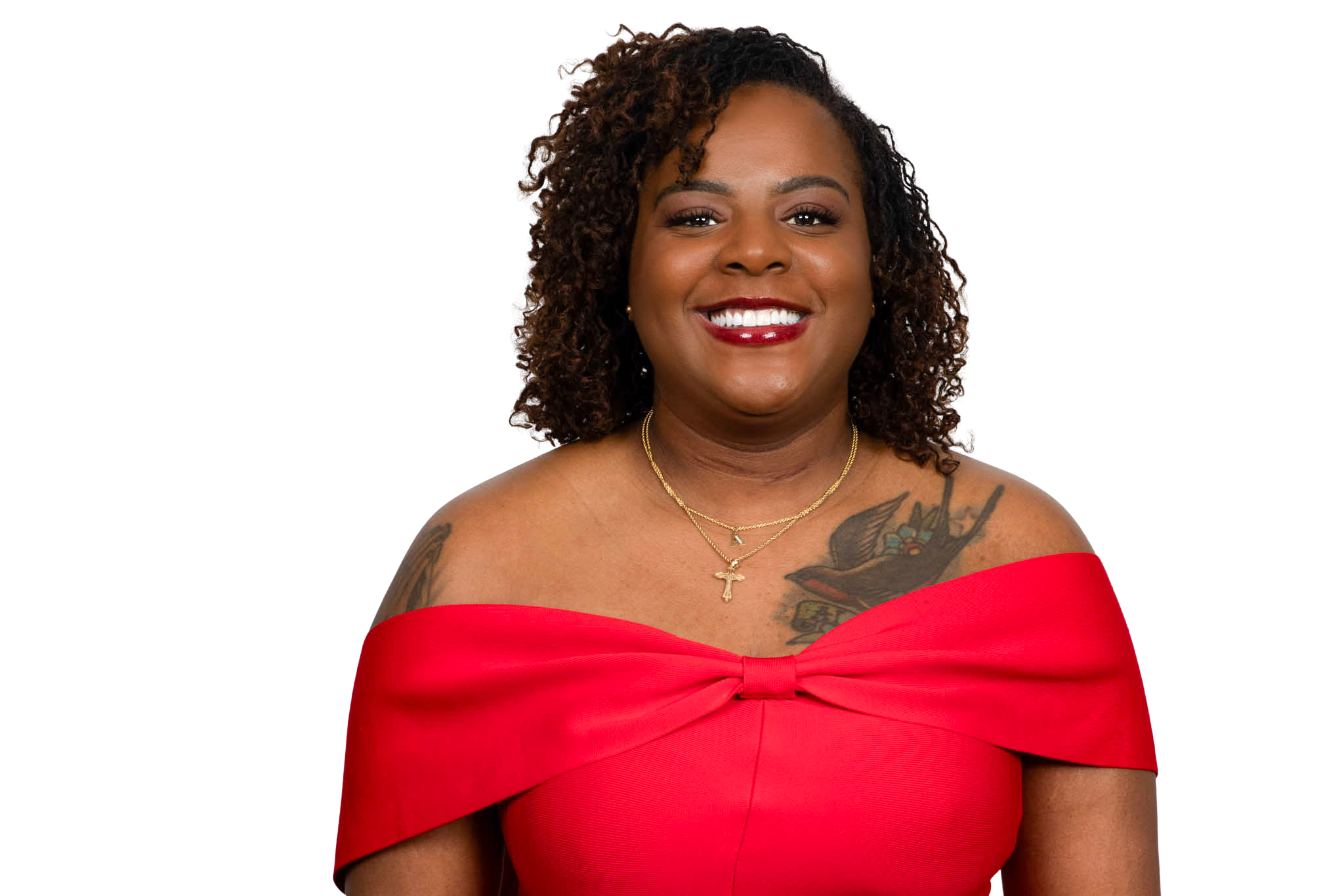 Woman with loc'd hairstyle wearing red dress and cross necklace, smiling.